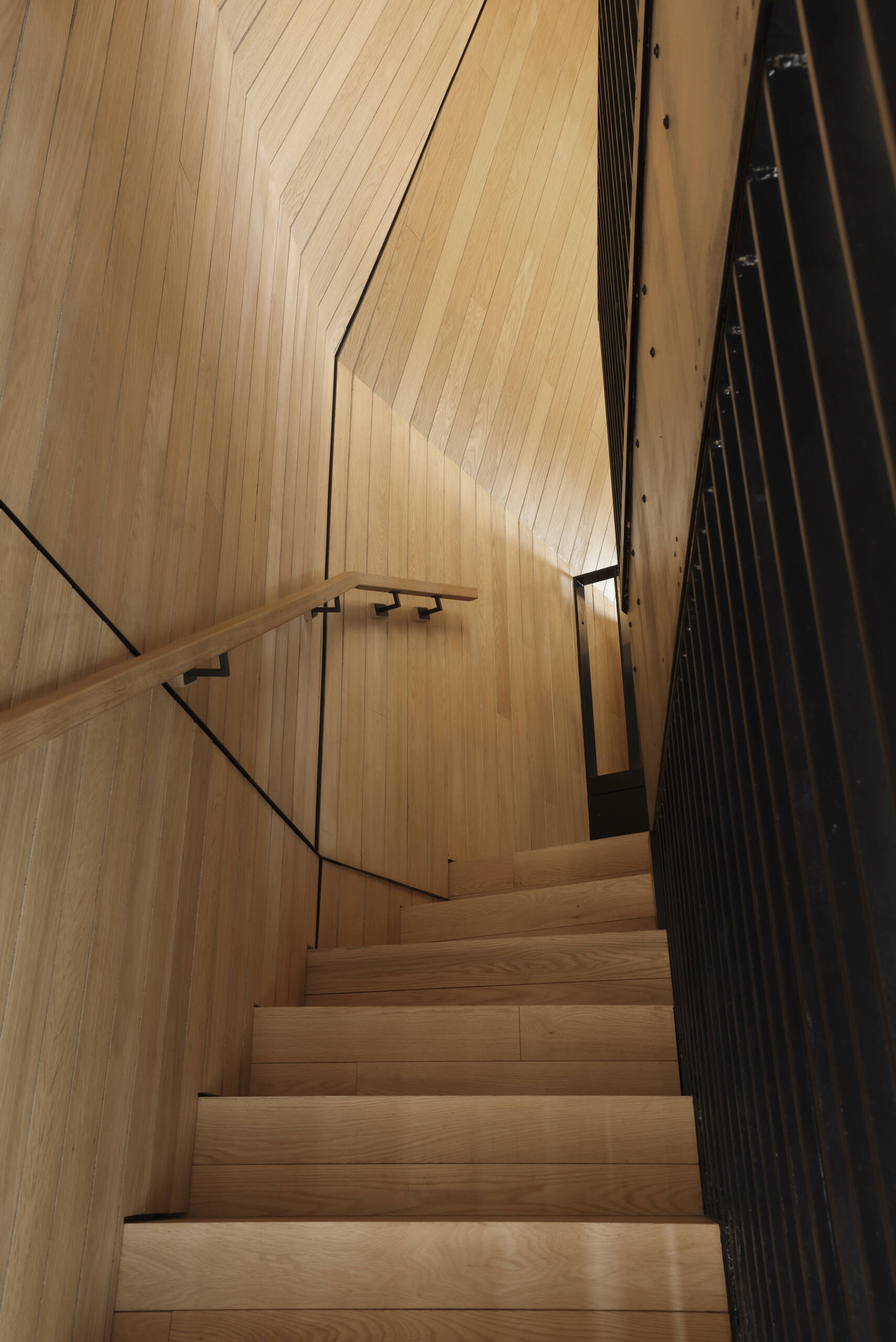 Inside this modern cottage, the atmosphere is warm and simple with white oak clad walls and polished concrete floors. The great room is organized into three zones for gathering, eating, and cooking, each set at its own elevation.