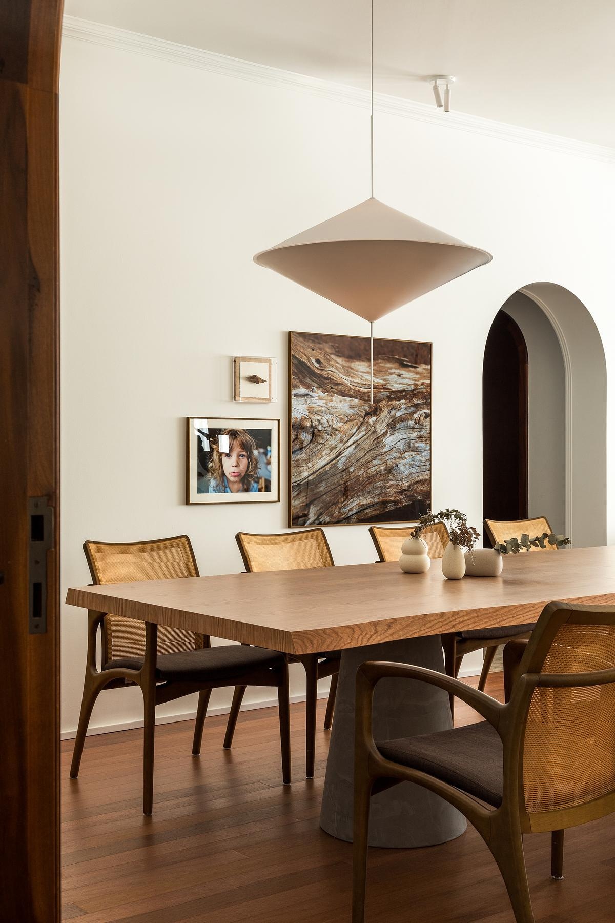 This dining area features Brazilian craftsmanship with the Bossa chair by Jader Almeida and a Concrete Table by Estudio Bola. Overhead, the Vertice Pendant by Waldir Junior draws the eye upward, echoing the curves of the surrounding arches.
