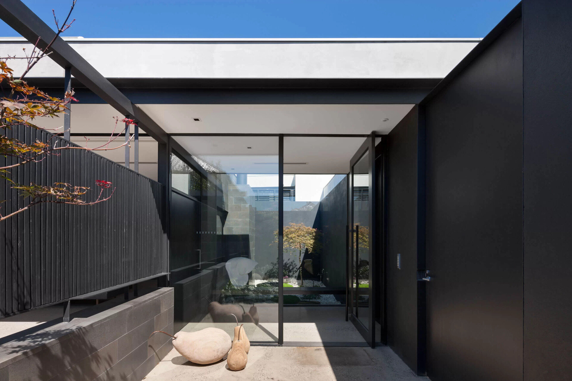 Once inside, the glass front door opens directly to an internal garden. This moment sets the tone for the rest of the house, where outside spaces sit alongside interior rooms.
