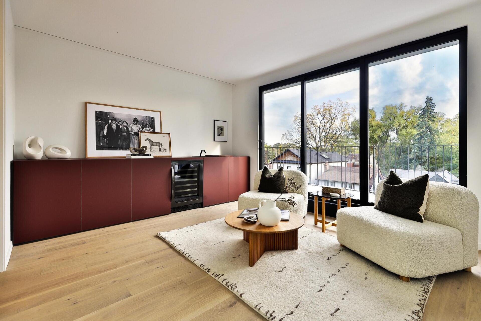 At the top of the home, a family room connects to the rooftop deck through a full glass wall, while a deep burgundy bar anchors the space, giving weight to the open view and complementing the calm interior palette.