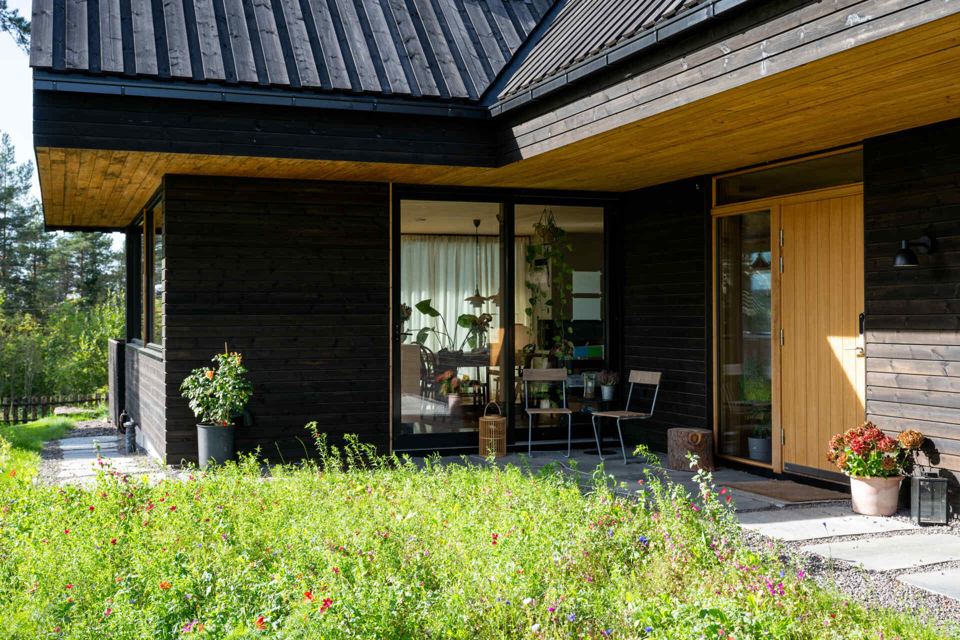 The house features a cross-gabled roof, dark timber cladding, and extended eaves, designed to harmonize with the surrounding pine forest.