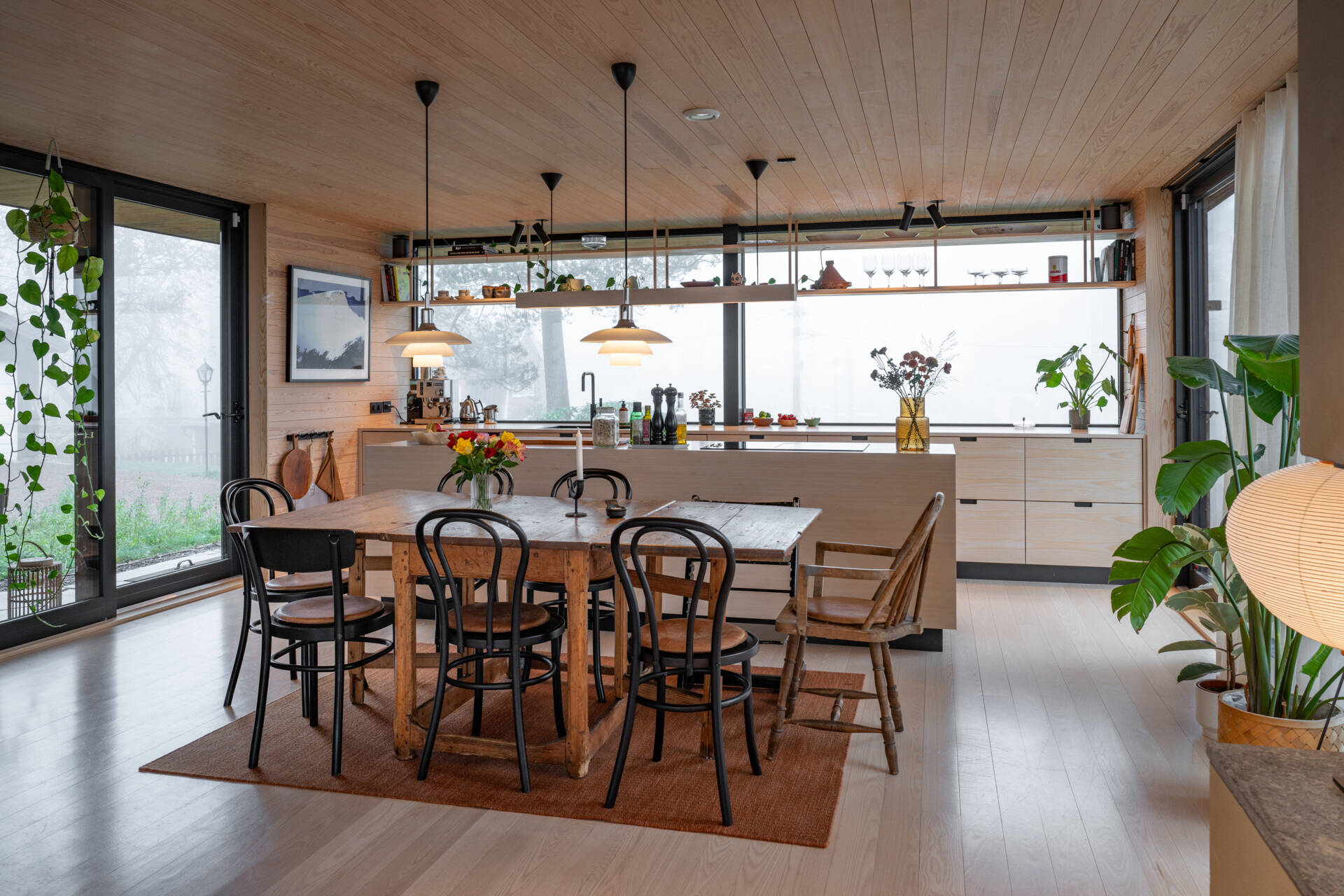 Adjacent to the living room, the dining area benefits from the same forest views. Its layout encourages gathering, while the connection to the outdoors gives meals a sense of openness and light.