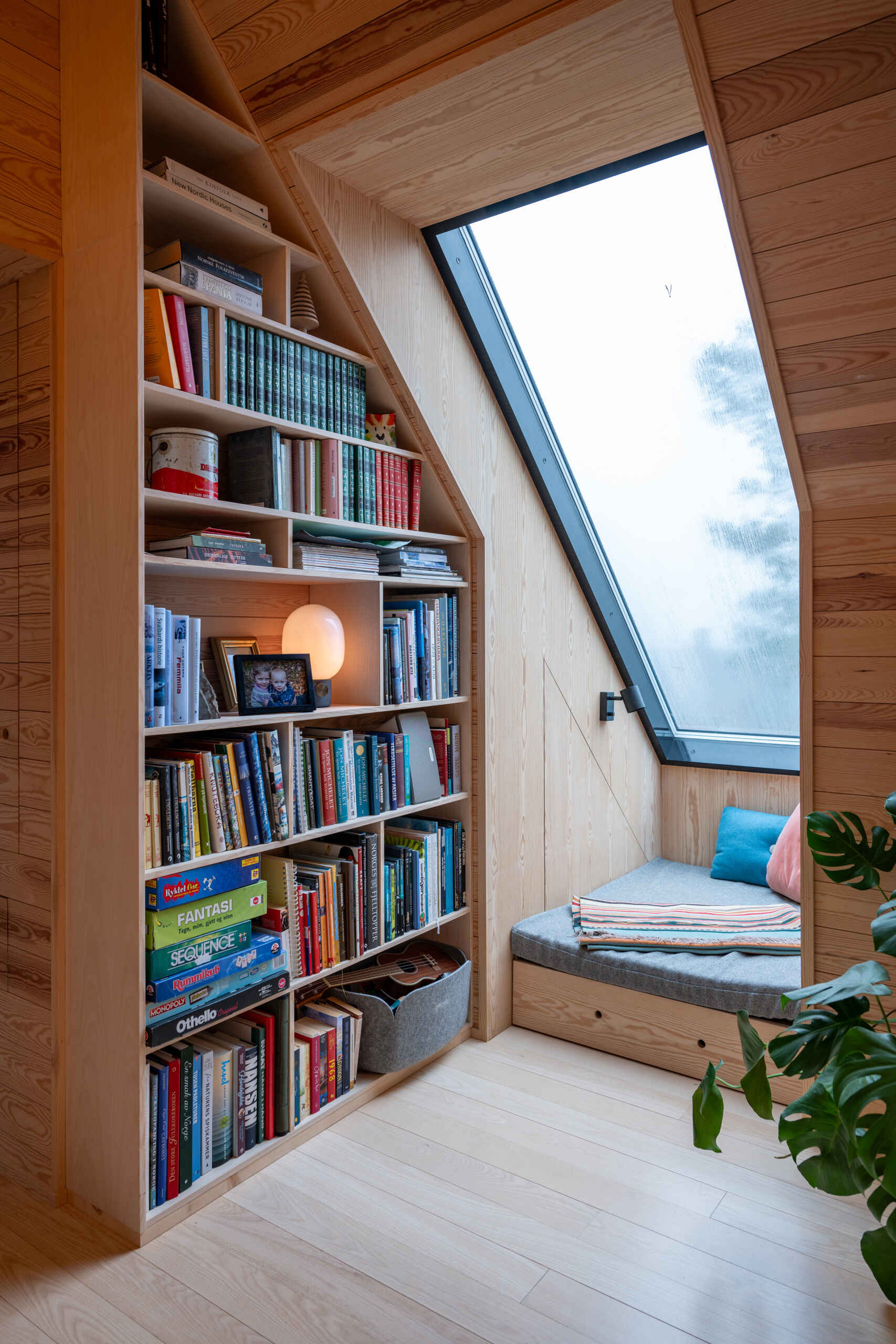 A small corner dedicated has been dedicated as a reading nook with custom shelving, providing a relaxing space for quiet activity. Natural light from roof windows highlights this area, making it an inviting spots to pause or reflect.
