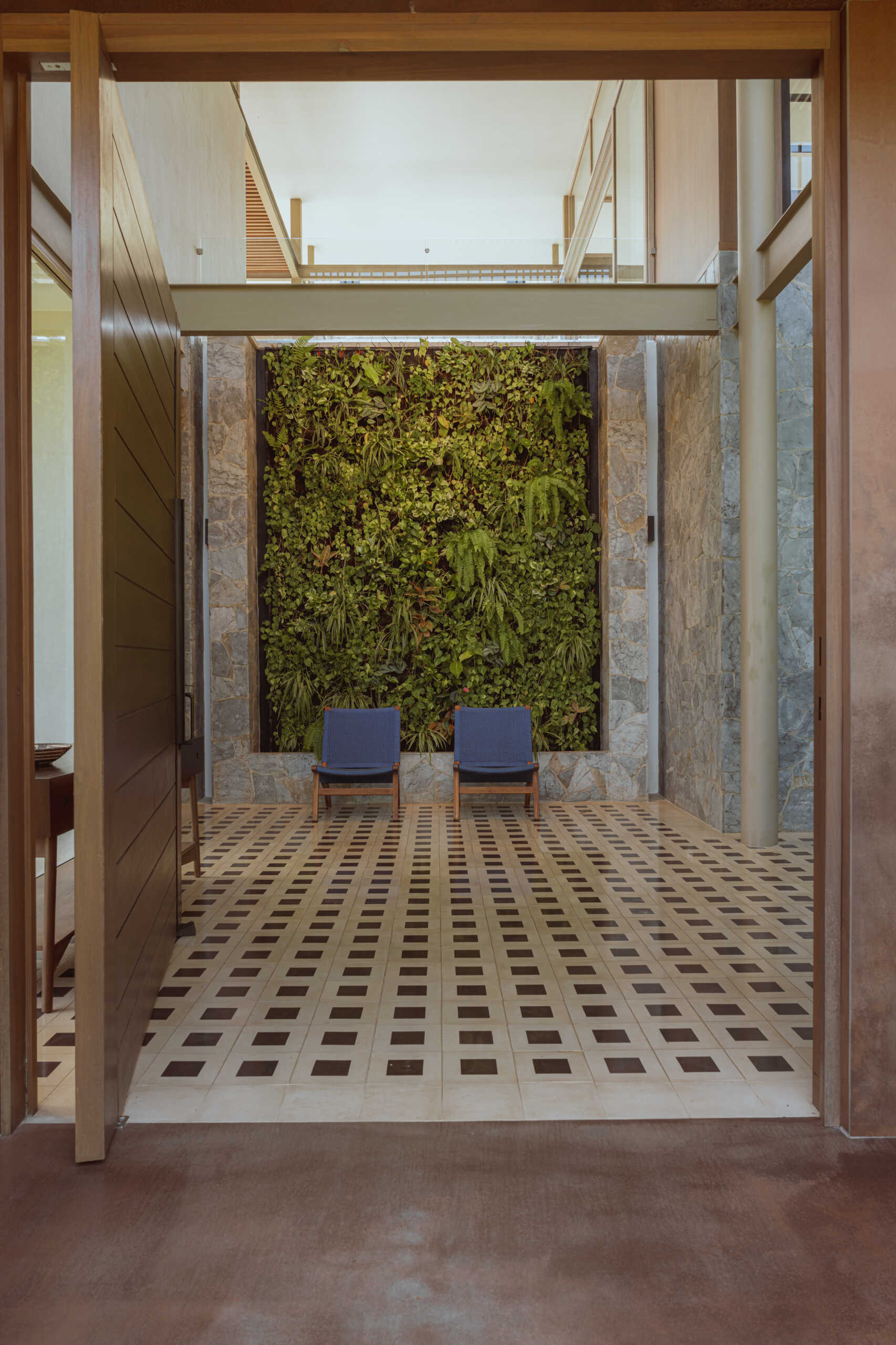 Approaching the villa, visitors arrive at a planted terrace that softens the geometry of the structure. Greenery is part of the welcome, setting the tone for a home designed to breathe. A living wall greets you at the entrance, hinting at how vegetation moves through the entire experience of the house.