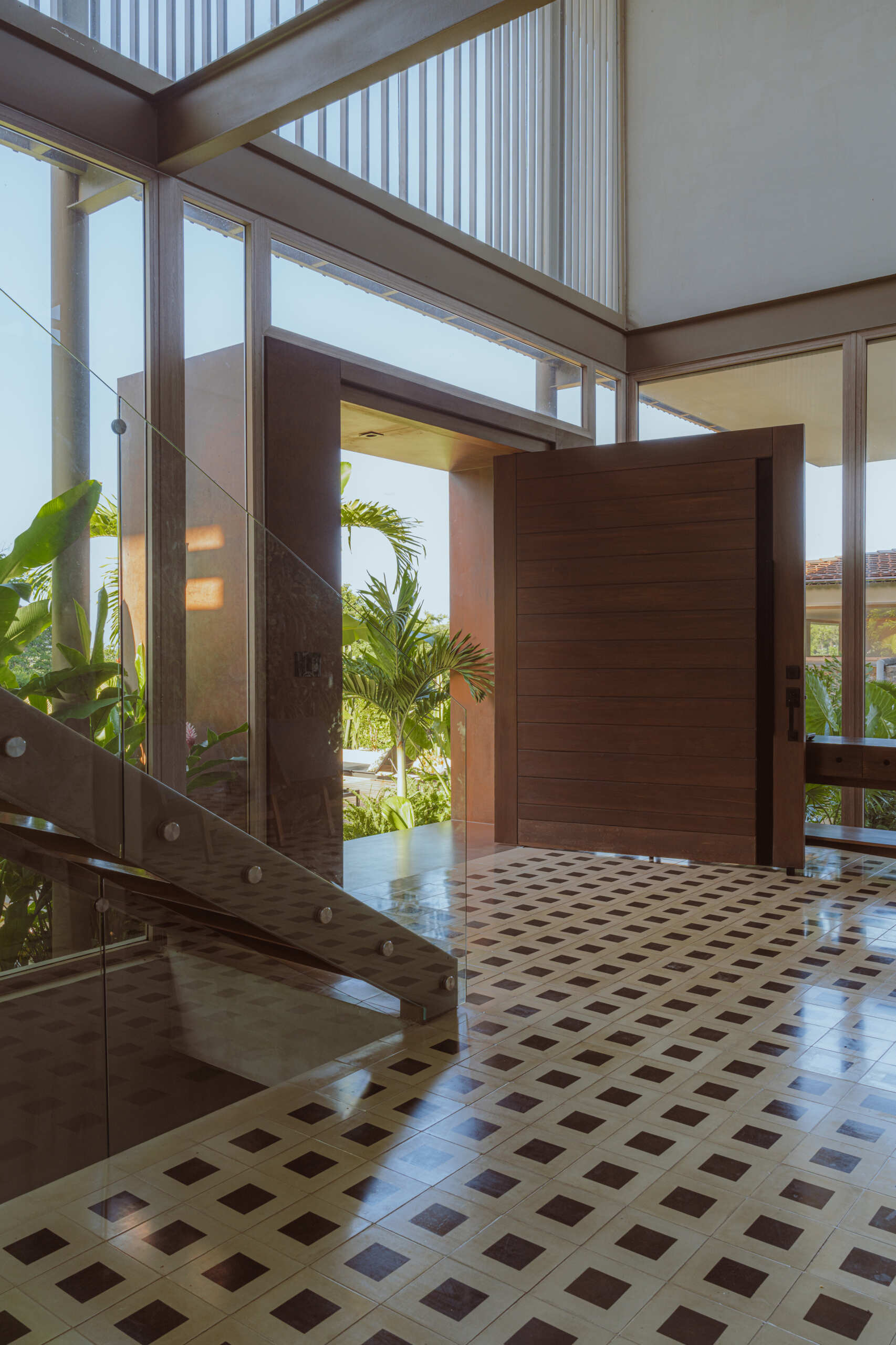 Inside the foyer, black and white tiles reference traditional Costa Rican patterns and connect the home to local craft. Cobalt blue armchairs introduce a bold moment of color that mirrors the tones of the sky and connects the interior to the surrounding landscape. From here, stairs guide the journey upward. The ascent reflects the concept of the home, with each step revealing wider views and lighter materials.