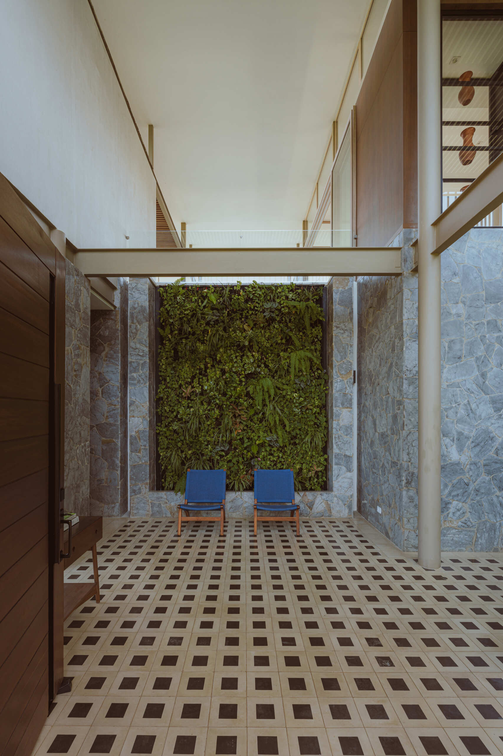Inside the foyer, black and white tiles reference traditional Costa Rican patterns and connect the home to local craft. Cobalt blue armchairs introduce a bold moment of color that mirrors the tones of the sky and connects the interior to the surrounding landscape. From here, stairs guide the journey upward. The ascent reflects the concept of the home, with each step revealing wider views and lighter materials.