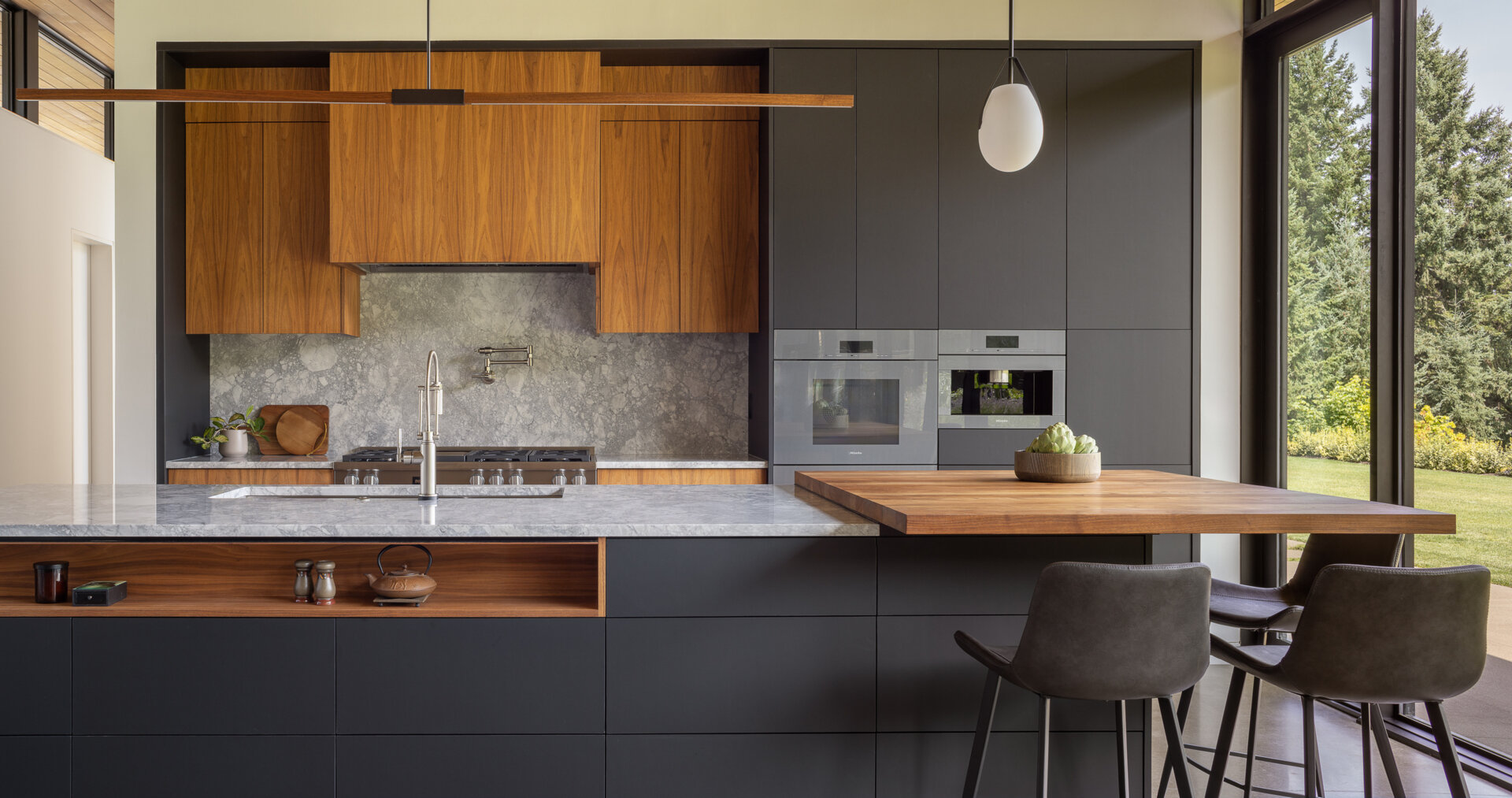 Designed around the golden ratio, this modern kitchen feels balanced and intentional, anchored by a large island with a slab countertop chosen by the clients. A walnut butcher block creates a dedicated coffee bar for slow mornings. The cabinetry stays clean and minimalist, with no pulls or visible hardware, a detail inspired by the clients’ engineering background.