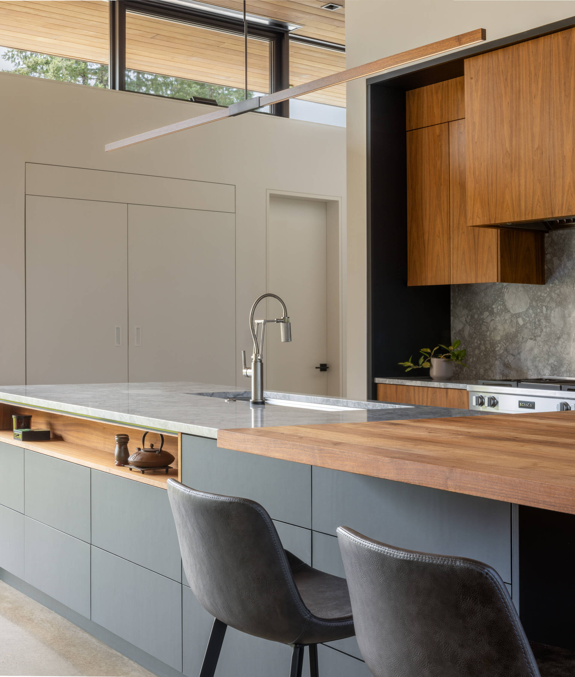 Designed around the golden ratio, this modern kitchen feels balanced and intentional, anchored by a large island with a slab countertop chosen by the clients. A walnut butcher block creates a dedicated coffee bar for slow mornings. The cabinetry stays clean and minimalist, with no pulls or visible hardware, a detail inspired by the clients’ engineering background.