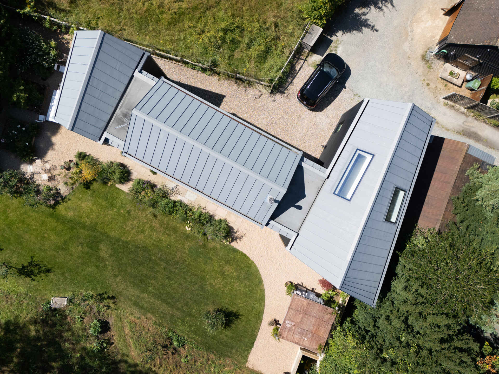 This rural home features dark timber that wraps the outer volumes, while a white central volume introduces a clear contrast. Zinc standing seam roofs complete the contemporary interpretation of traditional rural forms.