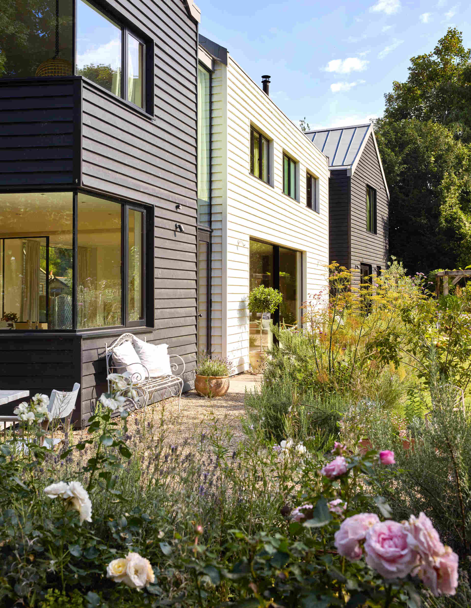 This rural home features dark timber that wraps the outer volumes, while a white central volume introduces a clear contrast. Zinc standing seam roofs complete the contemporary interpretation of traditional rural forms.
