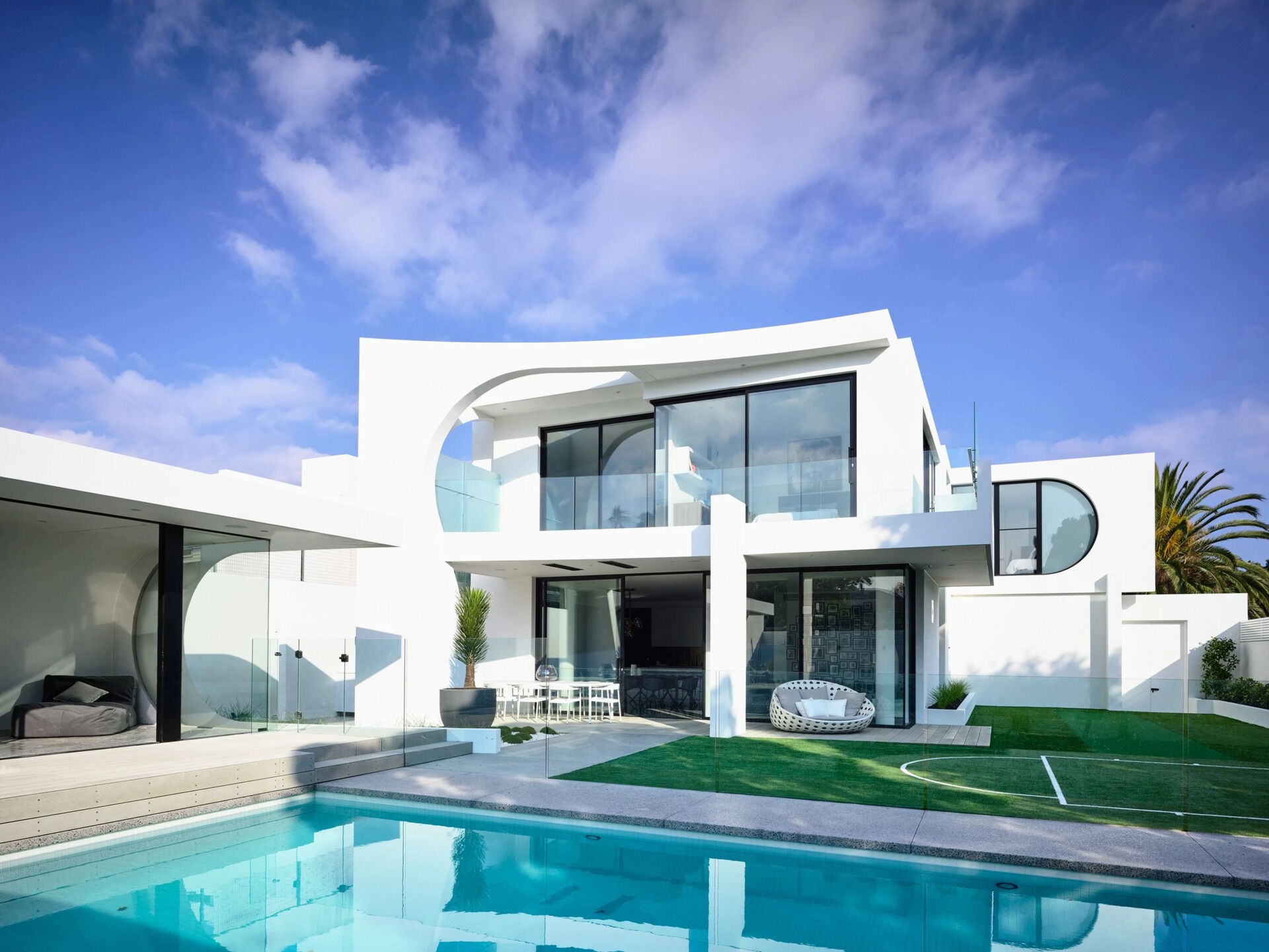 An infinity edge spa and pool sit beside a wave style pool house that offers shade and comfort after long days in the sun.