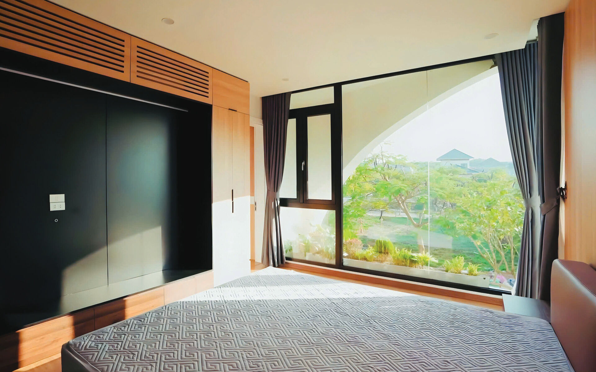 A bedroom in a modern home with views of greenery.