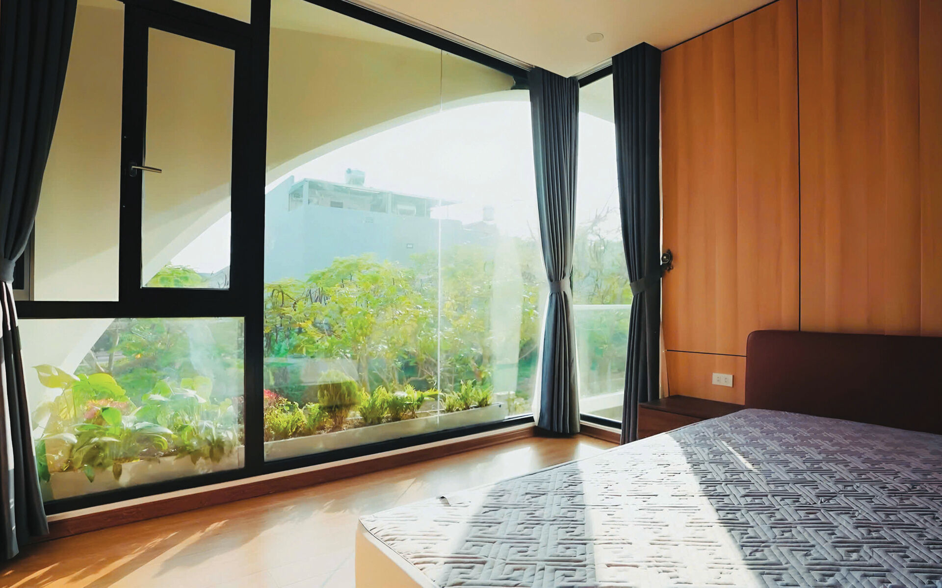 A bedroom in a modern home with views of greenery.