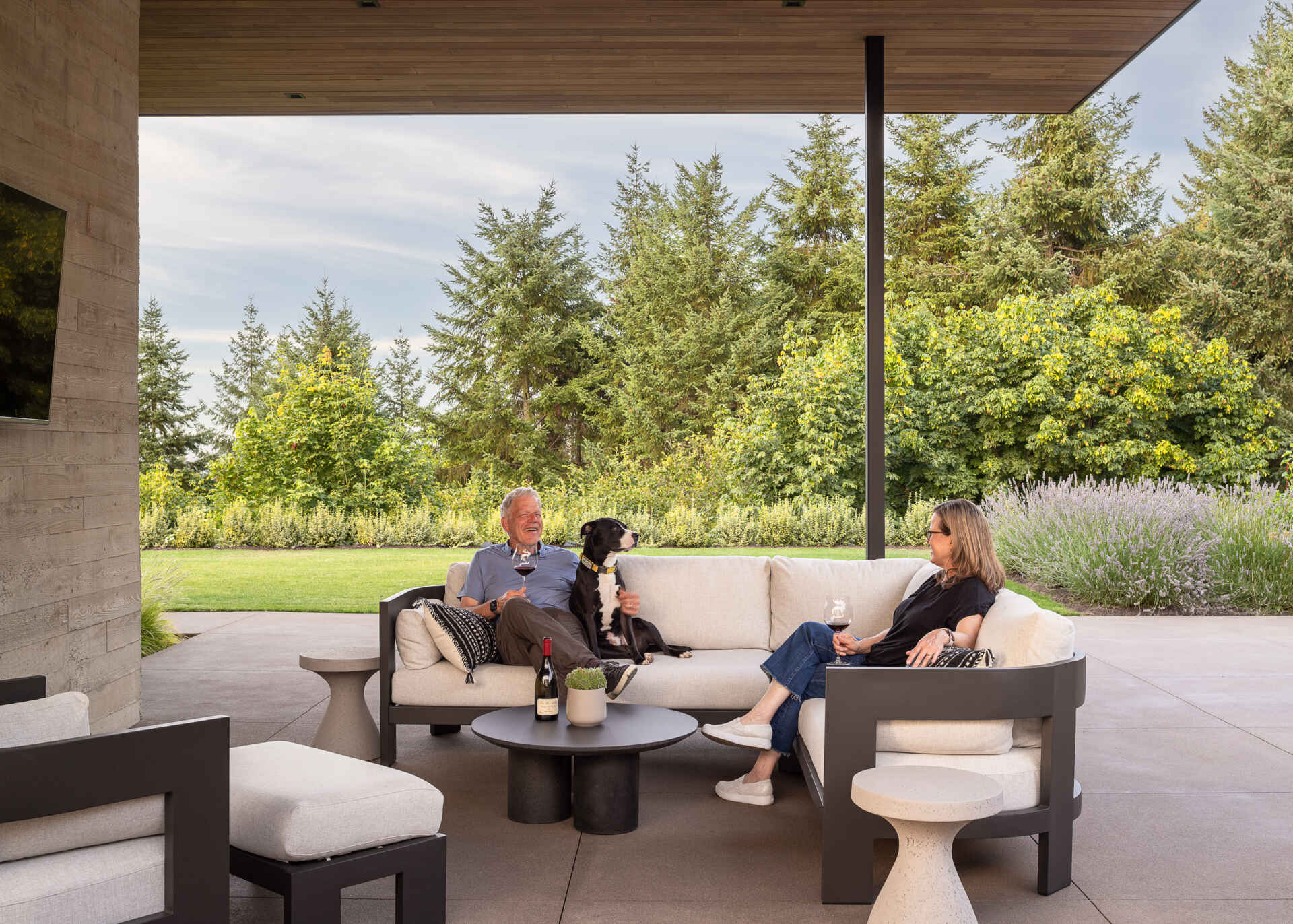 The covered patio extends directly from the great room, creating a seamless space for gatherings. The outdoor area takes cues from winery hospitality, shaped for a future where the clients may host tastings featuring their own wines. The firepit and bocce court add to the social atmosphere, all set against the backdrop of the vineyard and valley beyond.