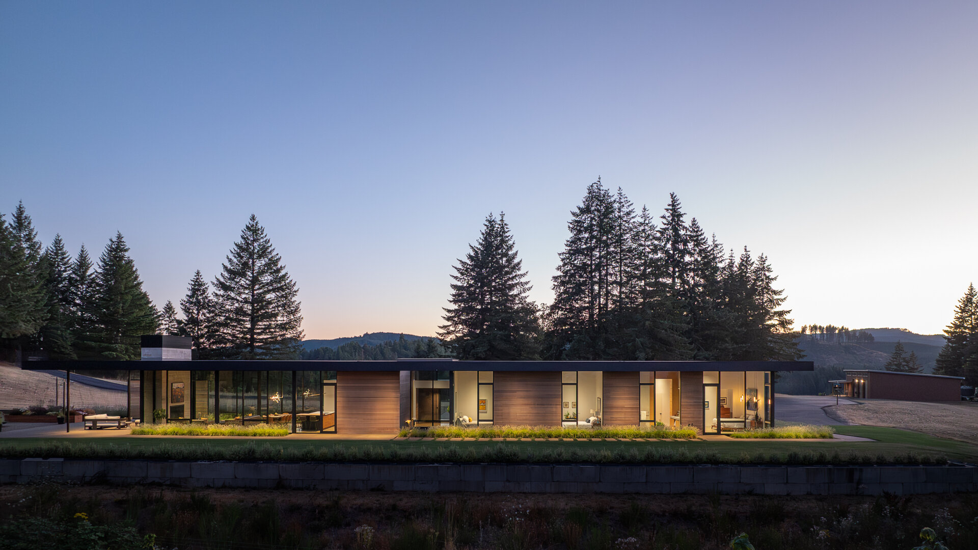 A quiet, cedar clad vineyard home emerges from the evergreens, designed with simple forms and warm minimalism that shape every room.