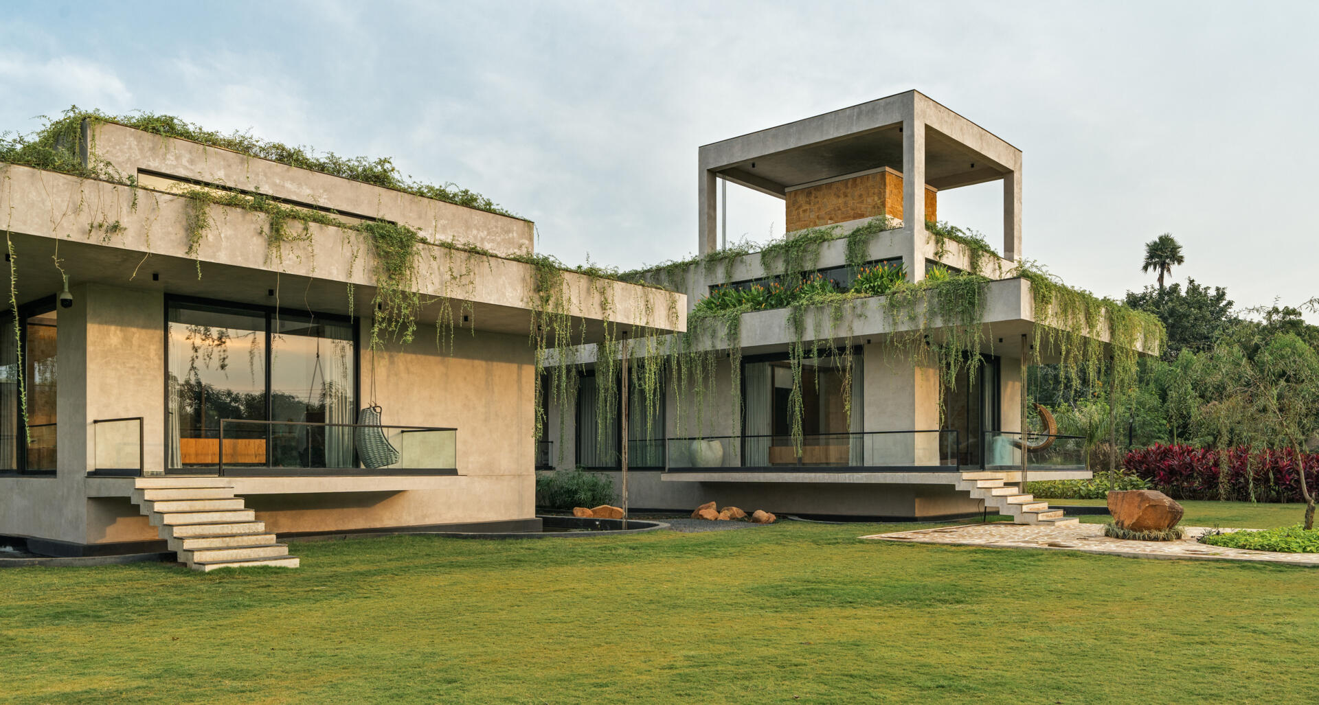 Long stone walls, floating pathways, and deep overhangs shape the architecture and guide movement through the home.