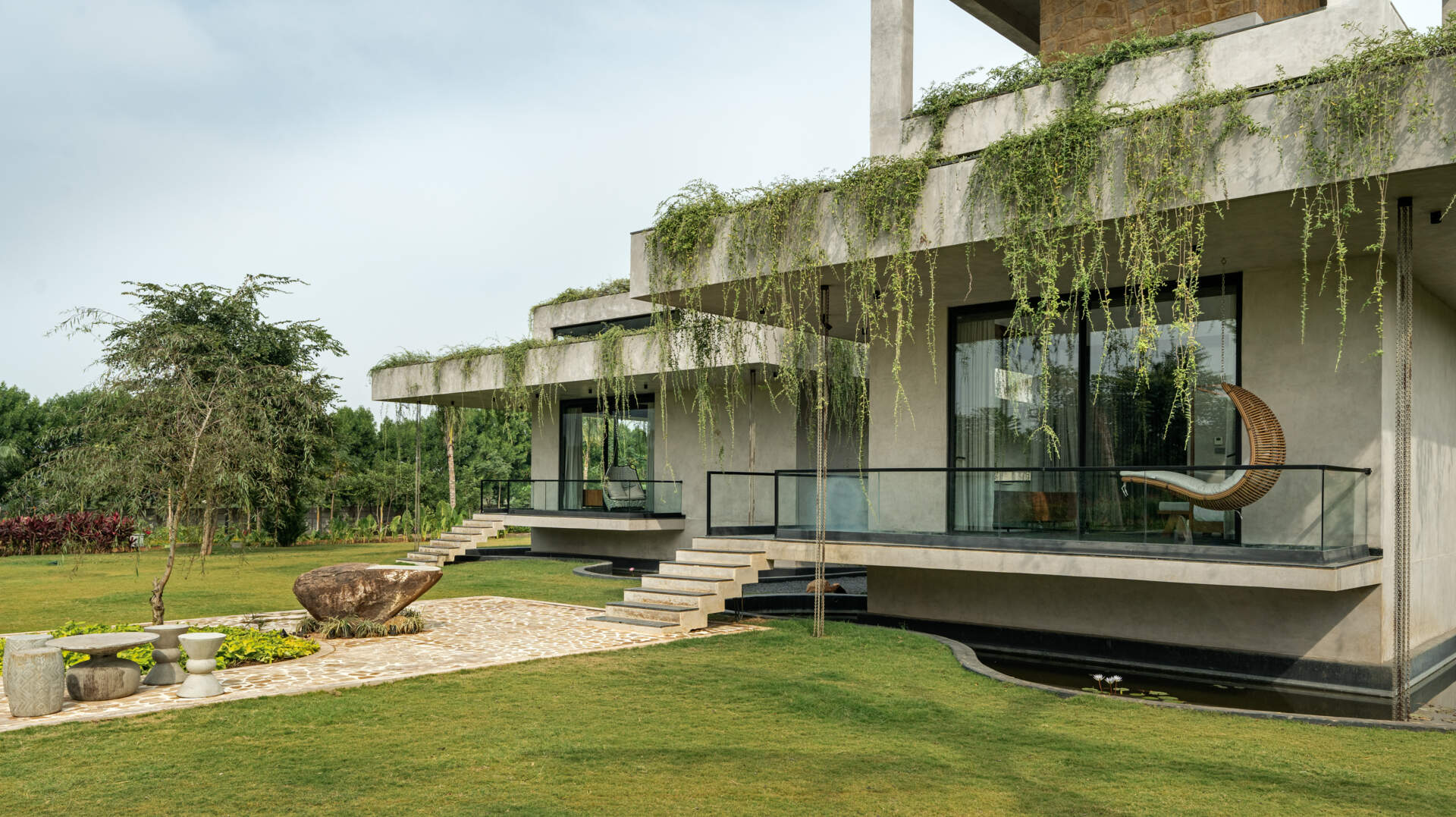 Long stone walls, floating pathways, and deep overhangs shape the architecture and guide movement through the home.