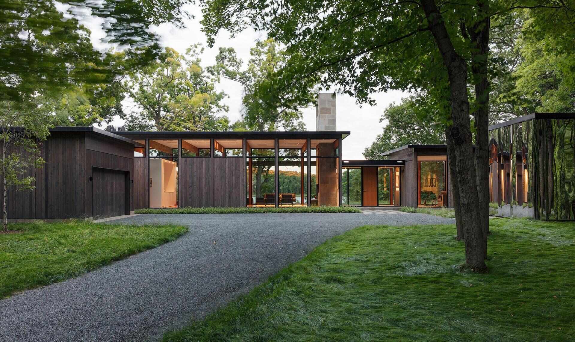 A calm modern home tucked into a Minnesota forest with views over a wetland and lake.