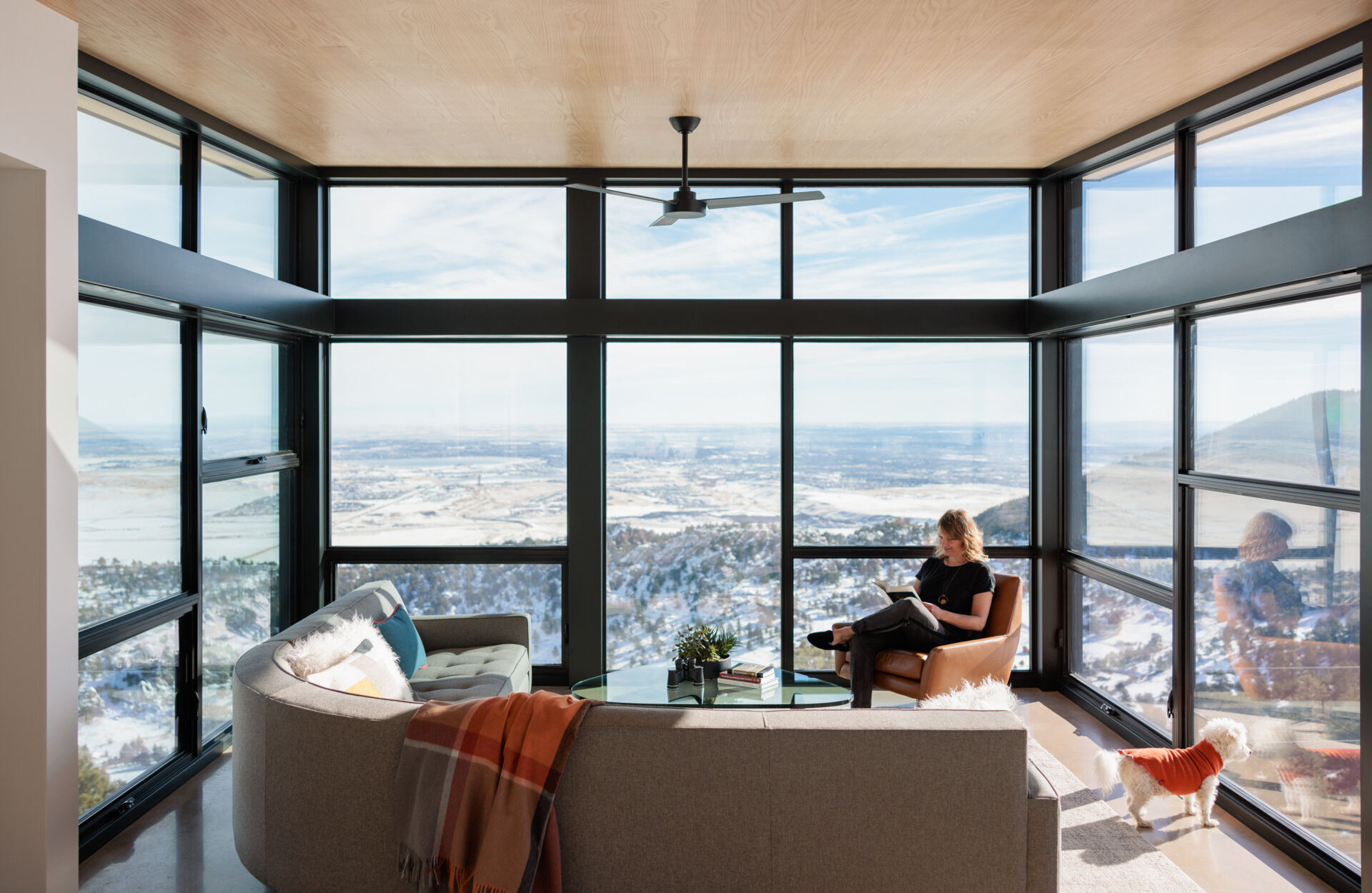 A glass encased living room that appears to float above the landscape. Floor to ceiling windows pull in mountain views and shift with light throughout the day.