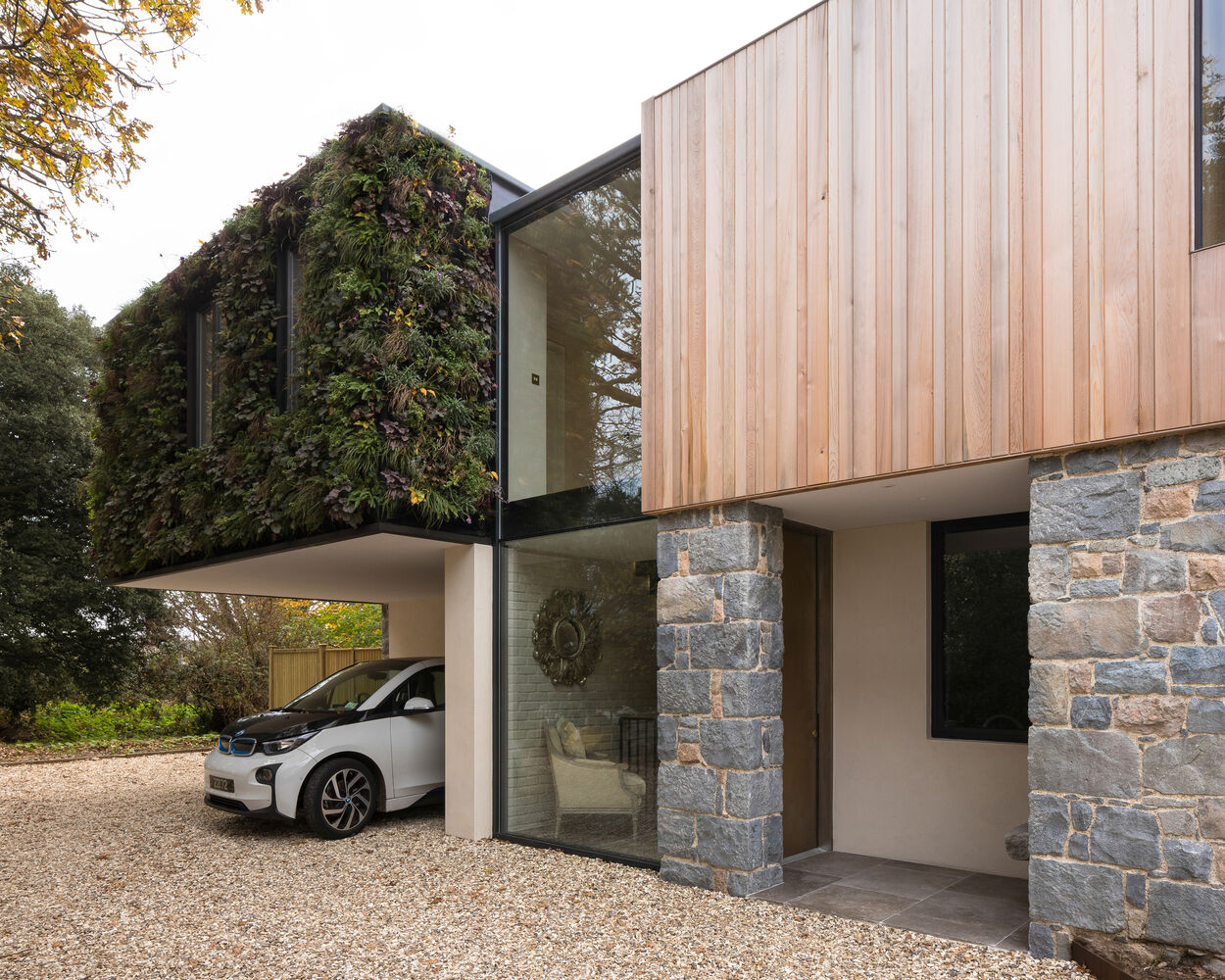 This modern home is wrapped in Guernsey granite, cedar cladding, and a living wall with 13 native species that soften the structure and blend it into the forested setting.