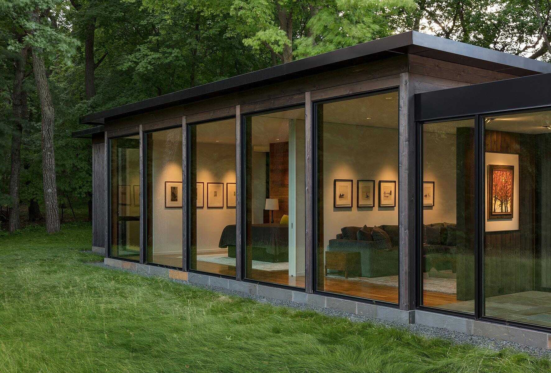 Dark stained cedar, large panes of glass and a bluestone base work together to blend the house into the forest.