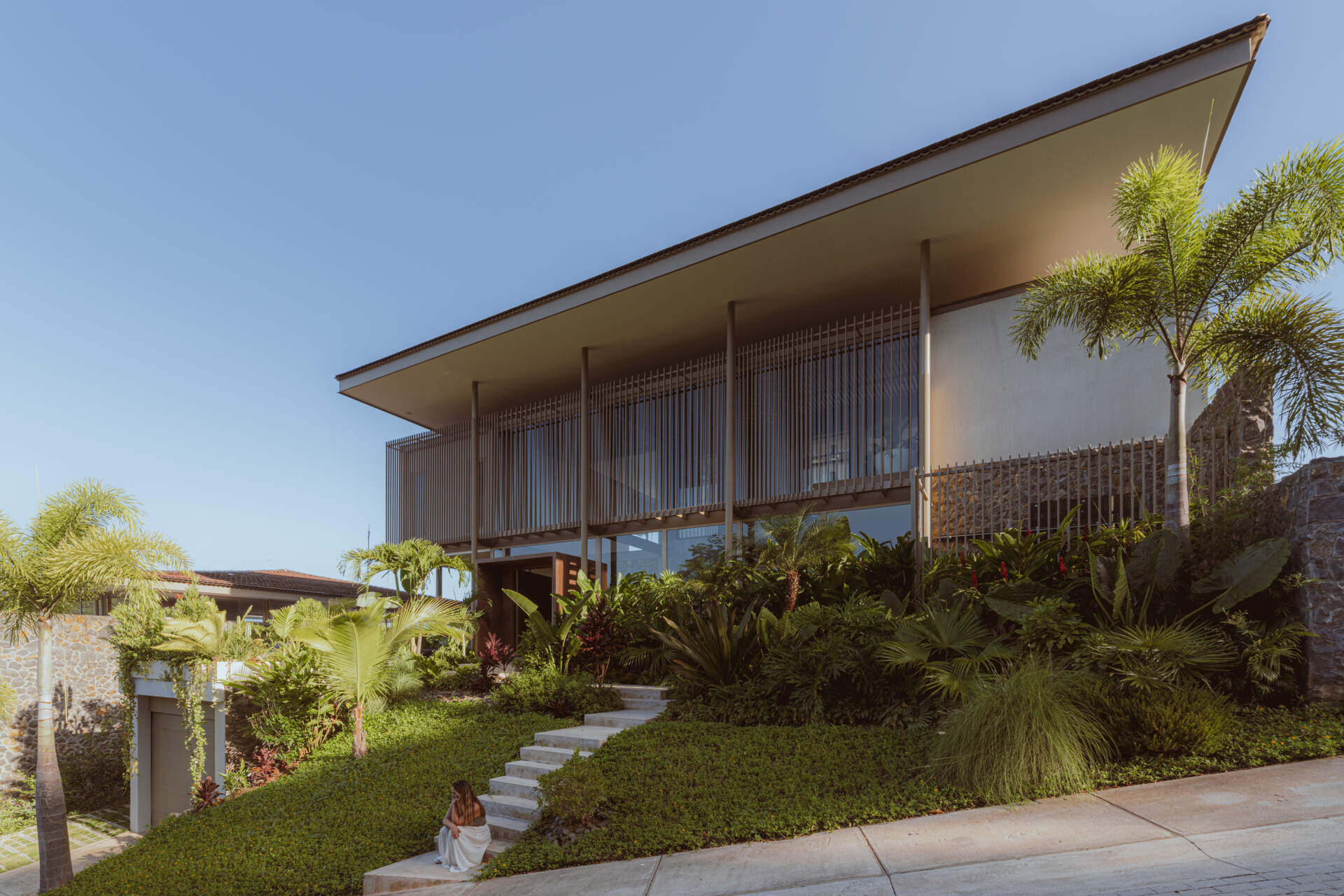 Approaching the villa, visitors arrive at a planted terrace that softens the geometry of the structure. Greenery is part of the welcome, setting the tone for a home designed to breathe. A living wall greets you at the entrance, hinting at how vegetation moves through the entire experience of the house.