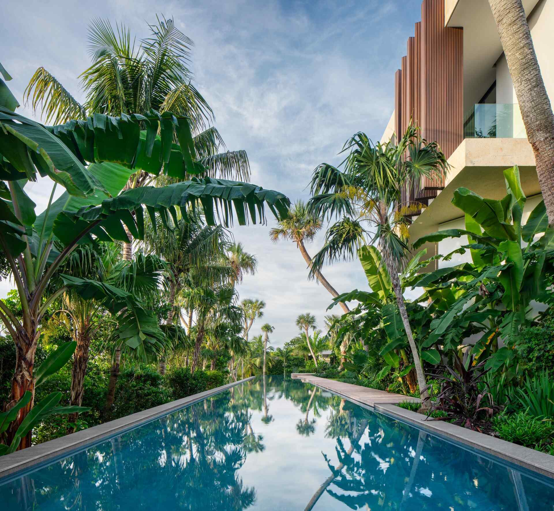 A tropical home with outdoor rooms and an infinity pool that blends naturally with the canal and surrounding greenery.