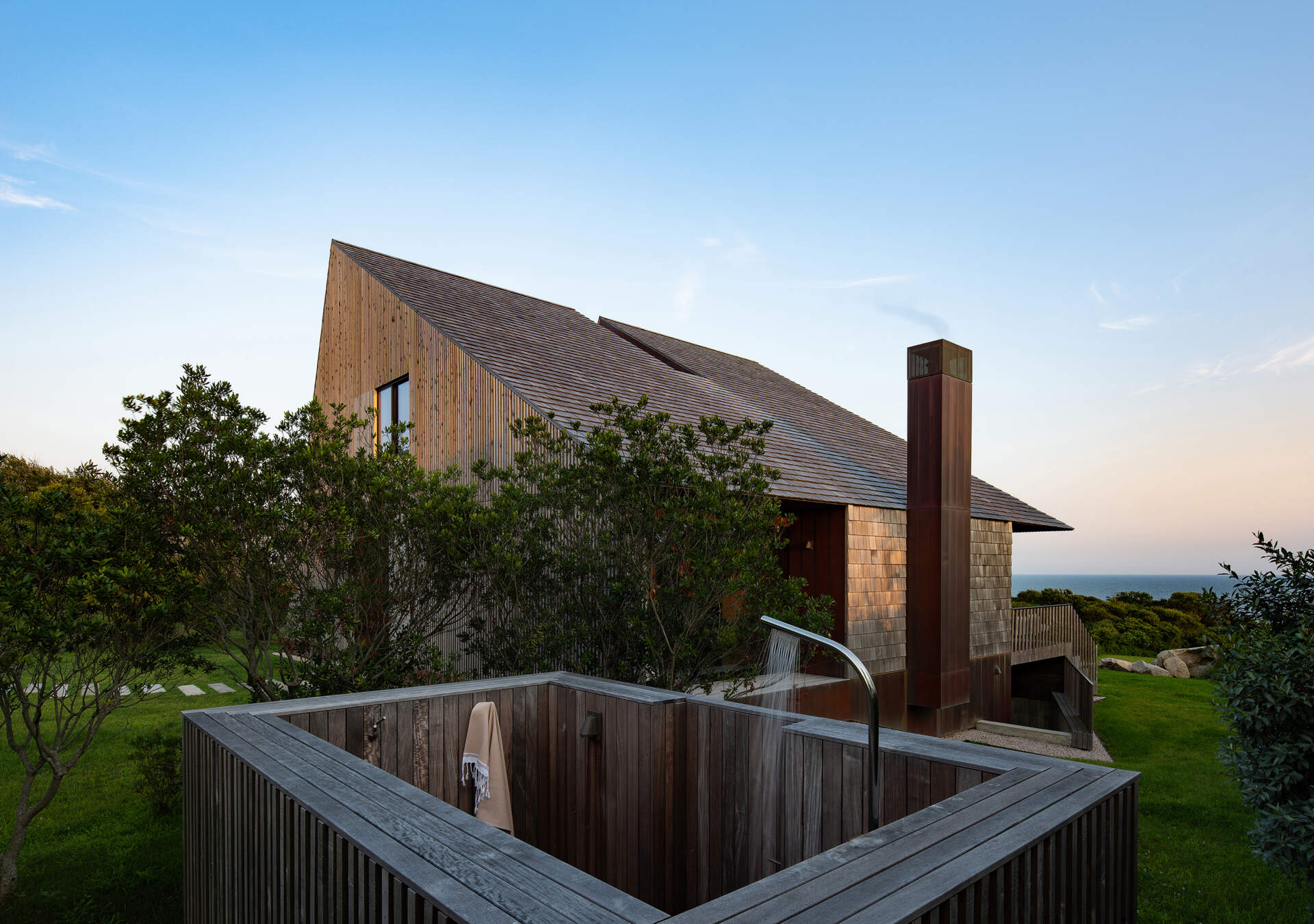 An outdoor shower surrounded by cedar and sky, celebrating the island’s rugged beauty through simplicity and natural materials.