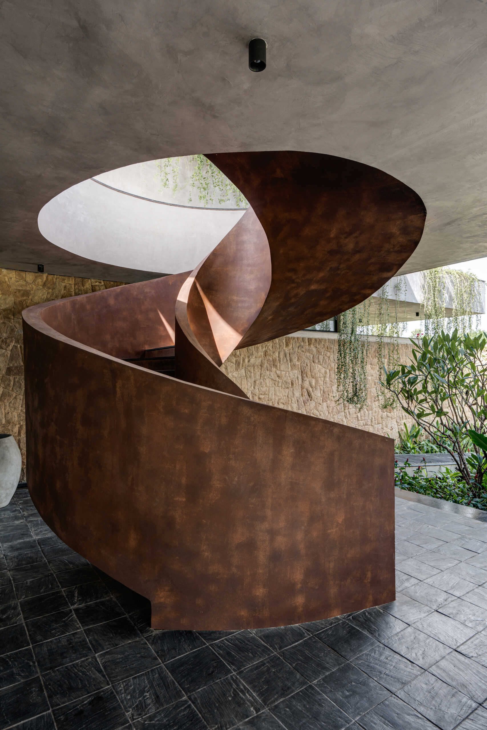 A sculptural spiral staircase contrasts with the floating architecture around it, anchoring the space.
