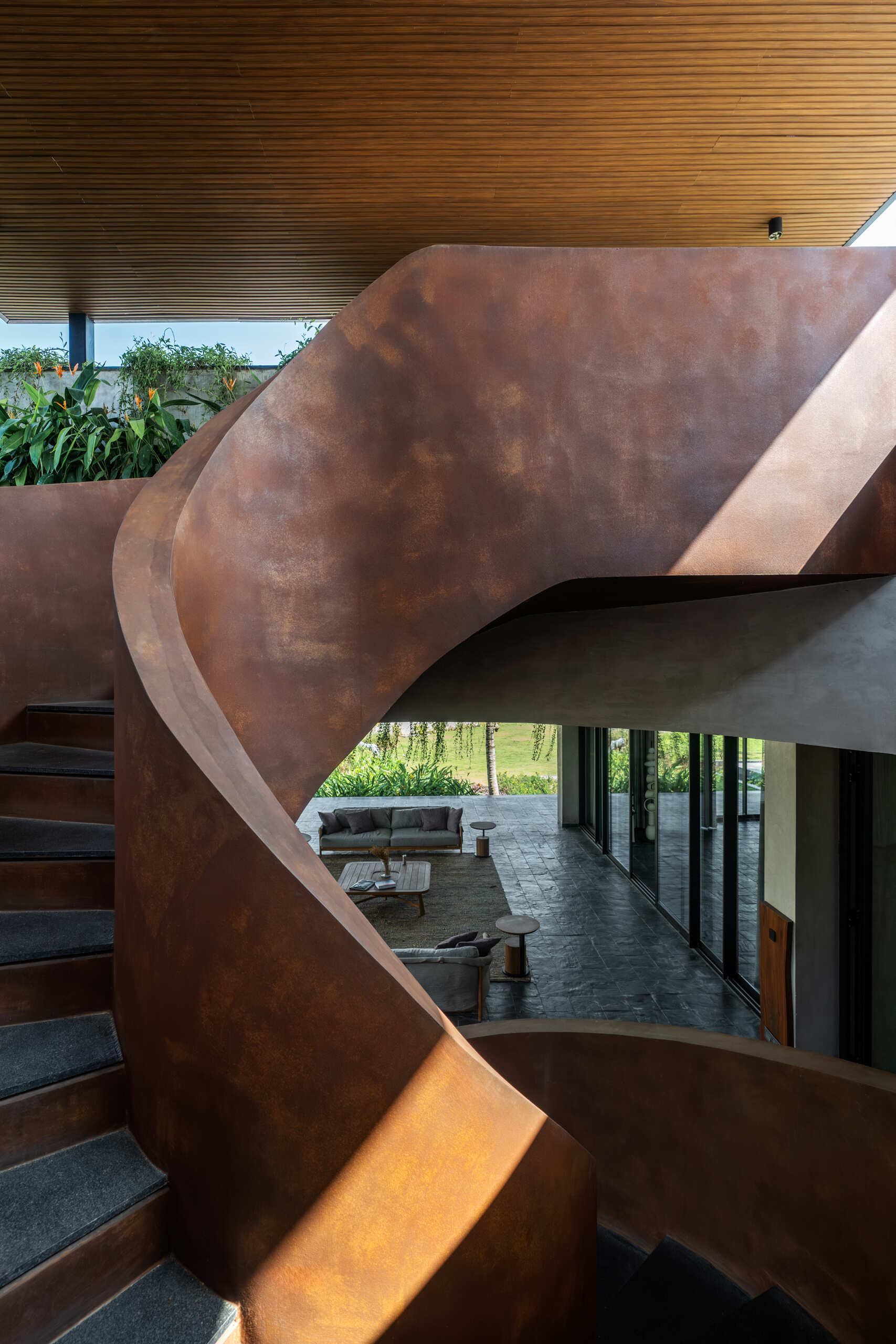 A sculptural spiral staircase contrasts with the floating architecture around it, anchoring the space.