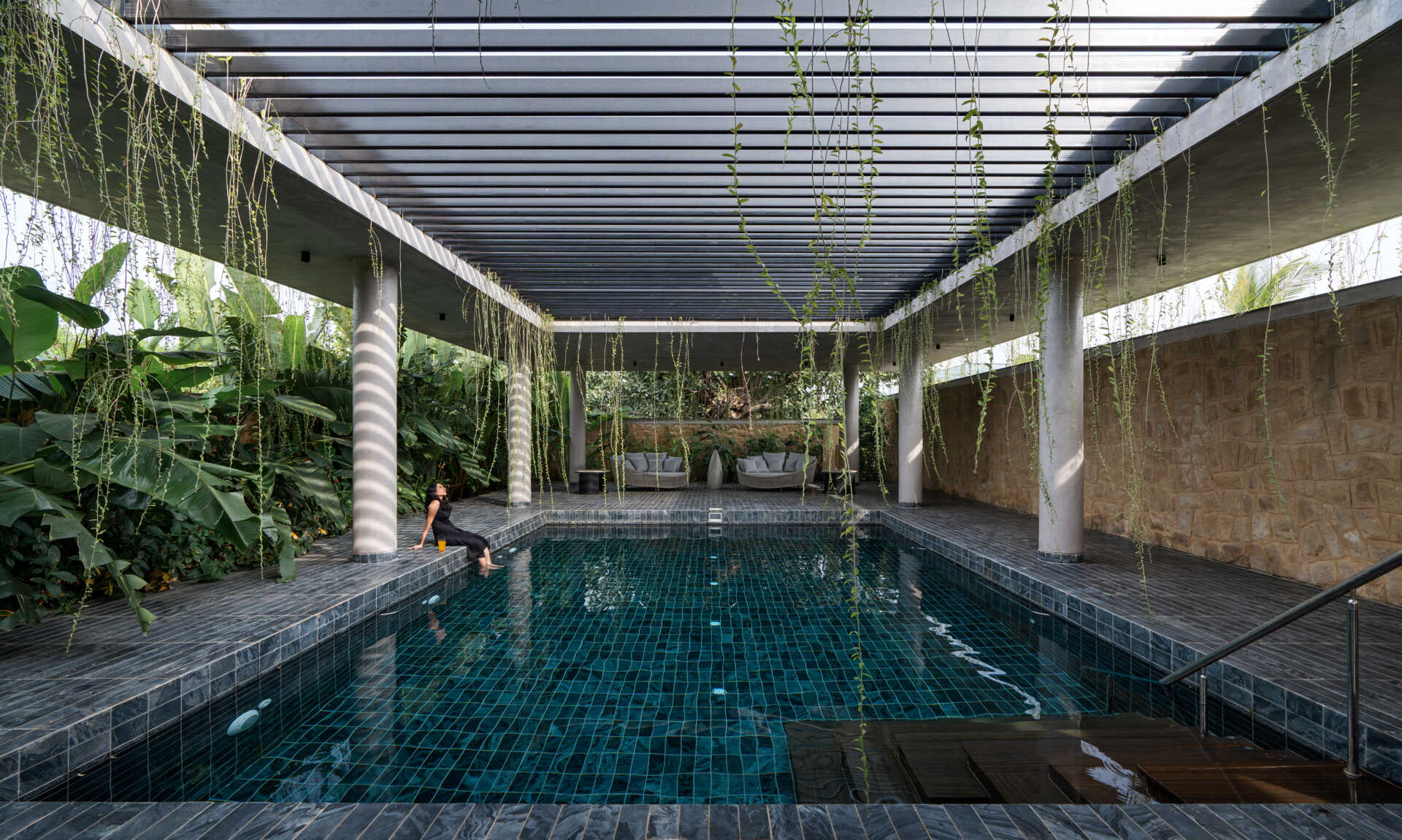 A private pool enclosed by stone walls and open sky, surrounded by lush planting.