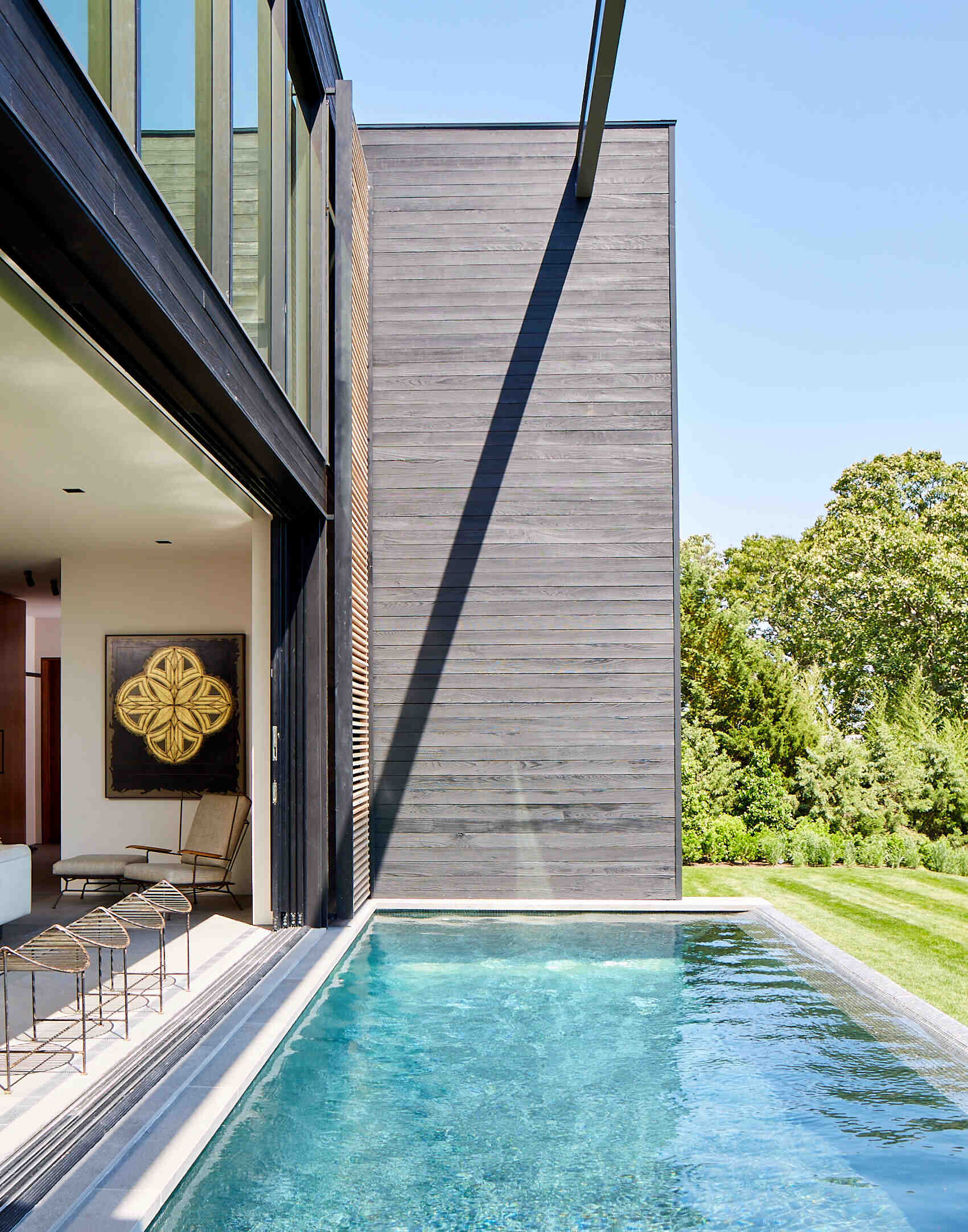 Massive glass panels transform the center of the home into a seamless indoor outdoor living space for pool days and sunset gatherings.