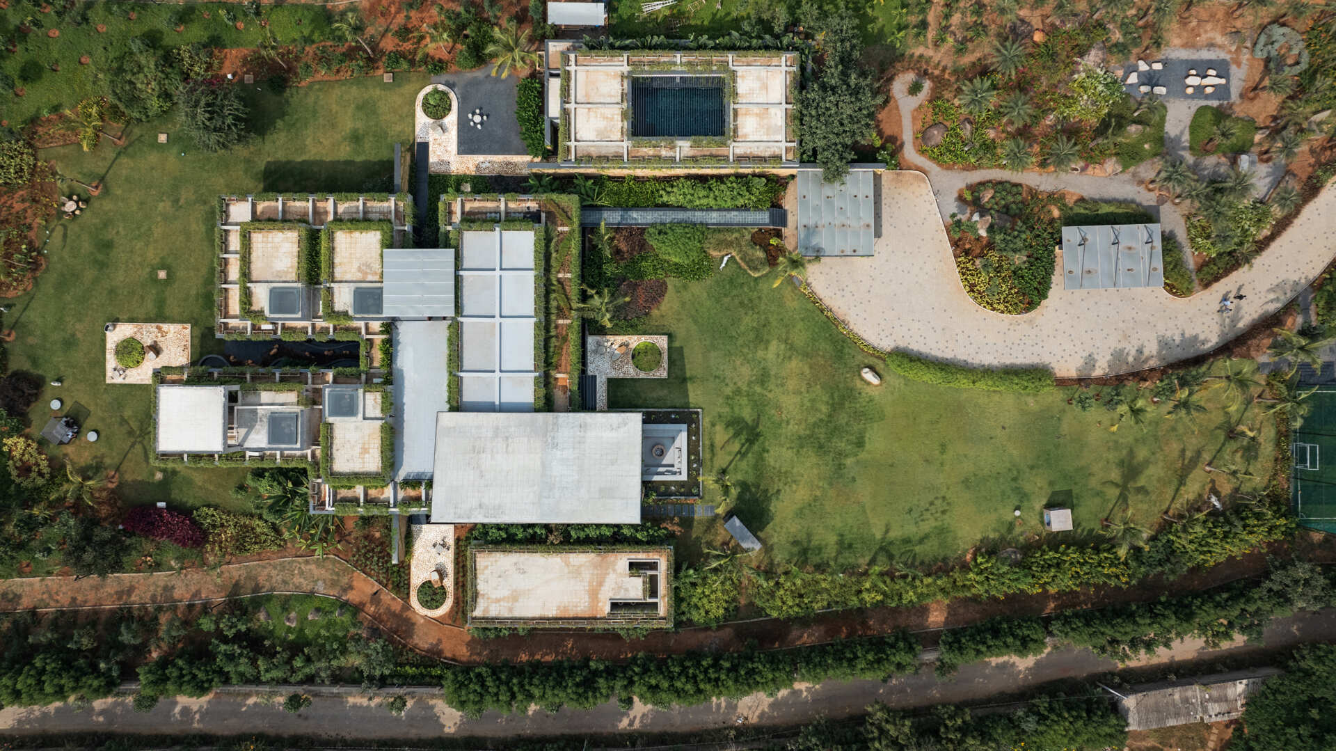 Long stone walls, floating pathways, and deep overhangs shape the architecture and guide movement through the home.