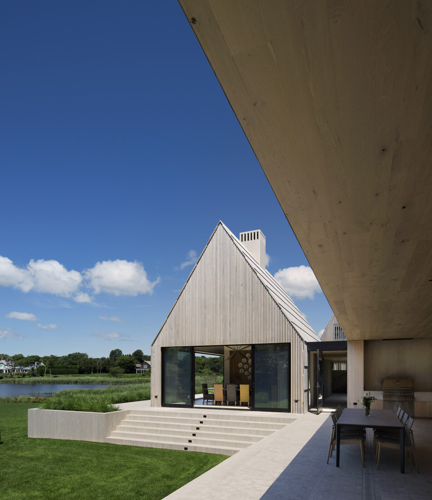 El zócalo de mármol posiciona la casa por encima del paisaje y gestiona las aguas pluviales con tranquila elegancia.