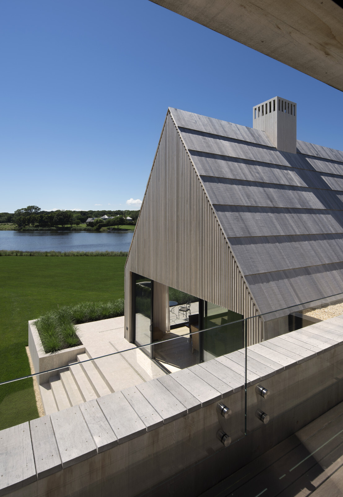 El zócalo de mármol posiciona la casa por encima del paisaje y gestiona las aguas pluviales con tranquila elegancia.