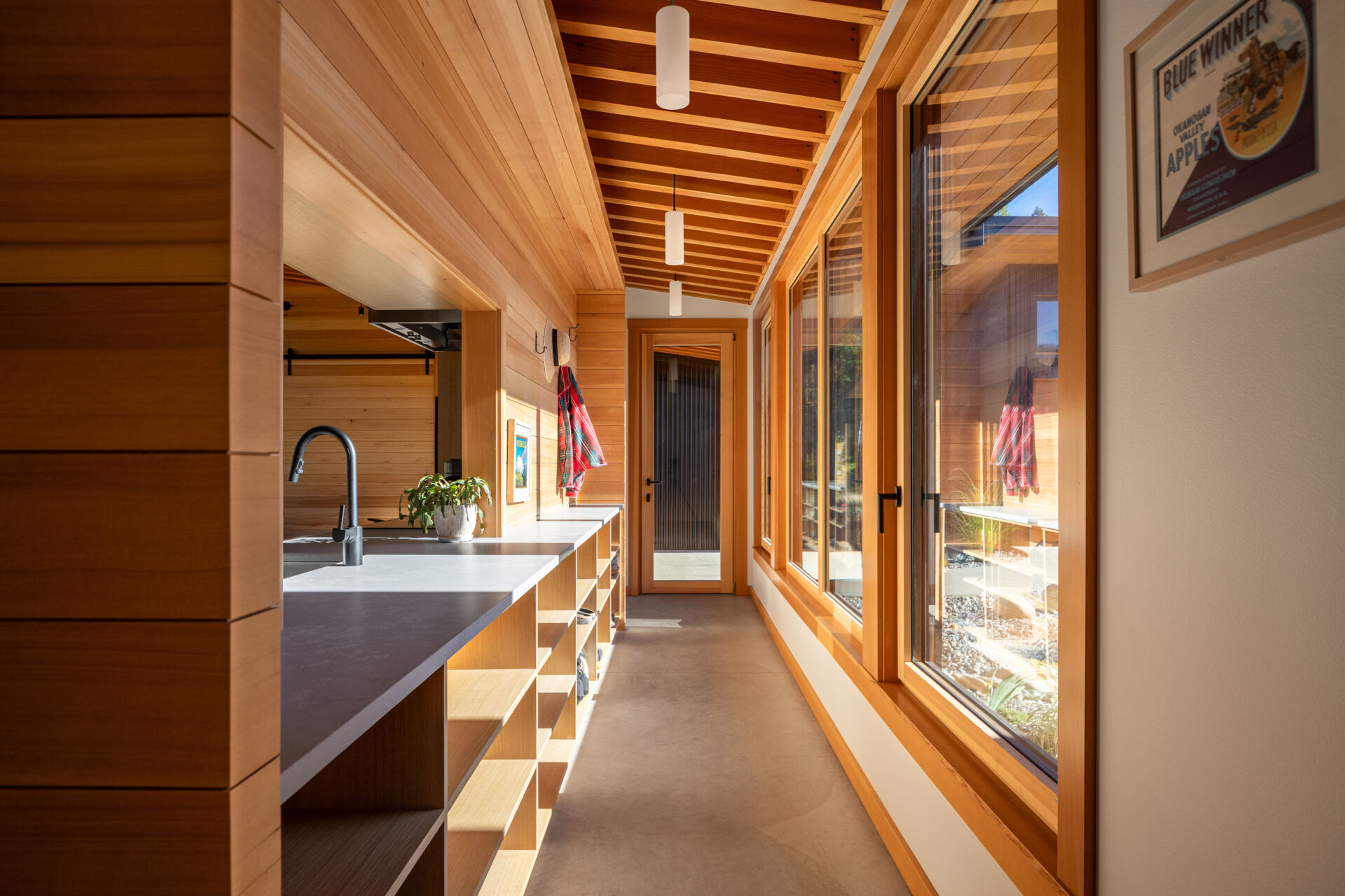 La cocina tiene vistas al prado, haciendo que la naturaleza se sienta parte de la habitación. Un recorte sobre el fregadero brinda visibilidad hacia la entrada, lo que permite a los propietarios ver llegar a los visitantes sin comprometer la sensación de privacidad de la casa.