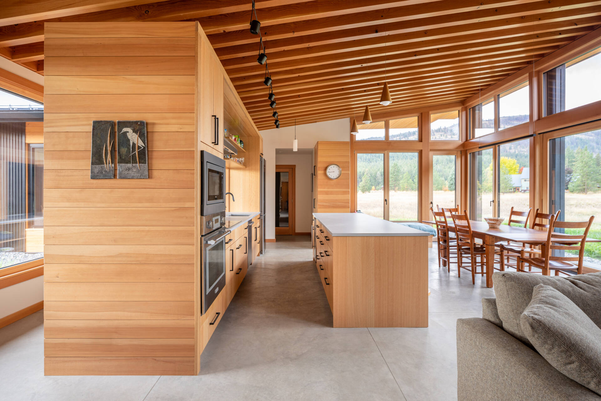 La cocina tiene vistas al prado, haciendo que la naturaleza se sienta parte de la habitación. Un recorte sobre el fregadero brinda visibilidad hacia la entrada, lo que permite a los propietarios ver llegar a los visitantes sin comprometer la sensación de privacidad de la casa.