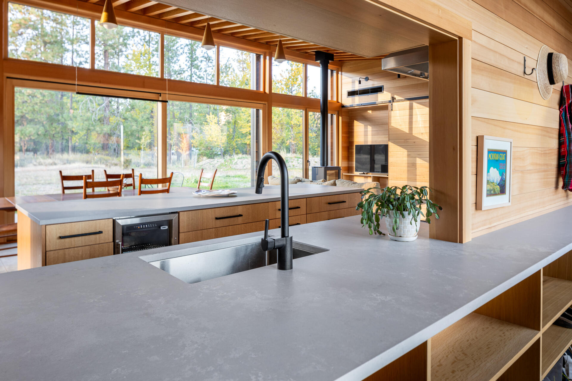 La cocina tiene vistas al prado, haciendo que la naturaleza se sienta parte de la habitación. Un recorte sobre el fregadero brinda visibilidad hacia la entrada, lo que permite a los propietarios ver llegar a los visitantes sin comprometer la sensación de privacidad de la casa.