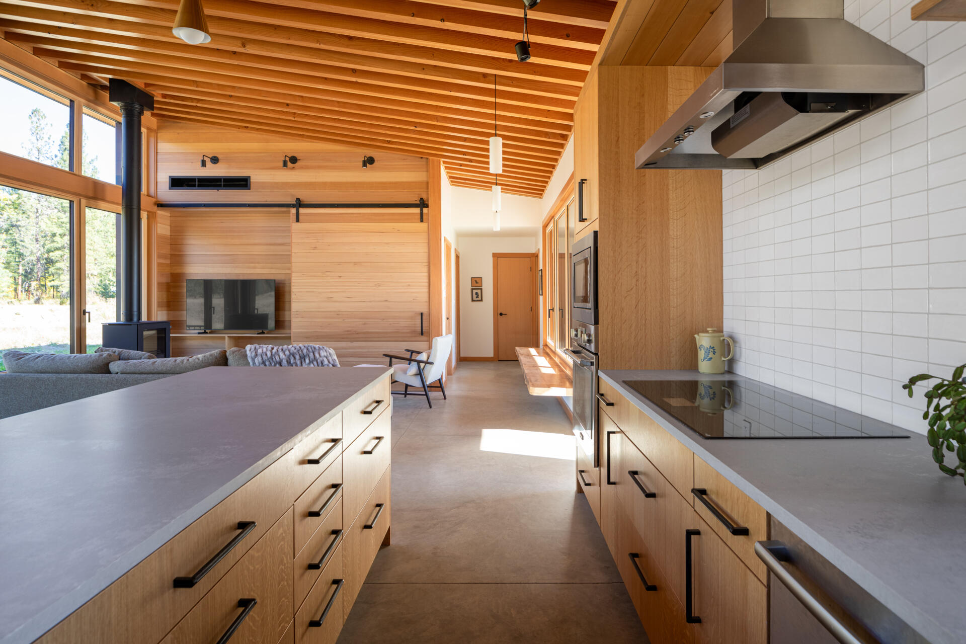 Los pisos de concreto mantienen todo conectado a tierra, mientras que la pared decorativa de madera de la sala de estar cuenta con puertas corredizas de estilo granero para ocultar el televisor o los estantes cuando sea necesario.