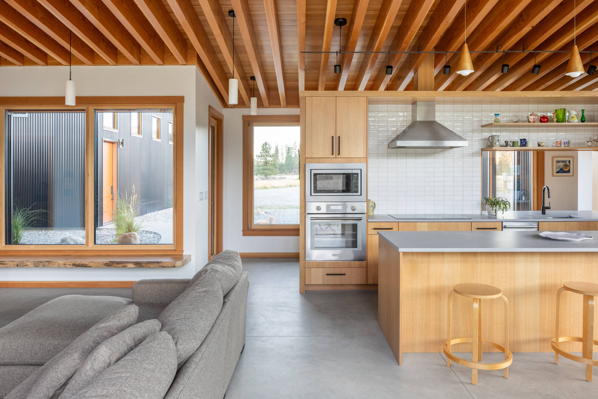 La cocina tiene vistas al prado, haciendo que la naturaleza se sienta parte de la habitación. Un recorte sobre el fregadero brinda visibilidad hacia la entrada, lo que permite a los propietarios ver llegar a los visitantes sin comprometer la sensación de privacidad de la casa.