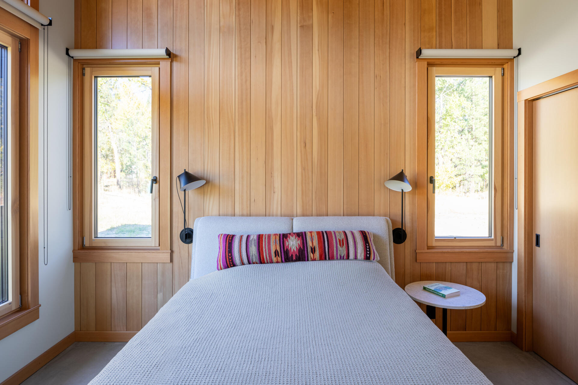 Los dormitorios están construidos alrededor del cielo y el valle. Los grandes ventanales capturan el cielo nocturno, dando la sensación de que el exterior es sólo una parte de la habitación. El baño en suite se mantiene limpio y tranquilo, diseñado para la relajación, con paredes cuadradas de azulejos grises y un tocador de madera flotante.