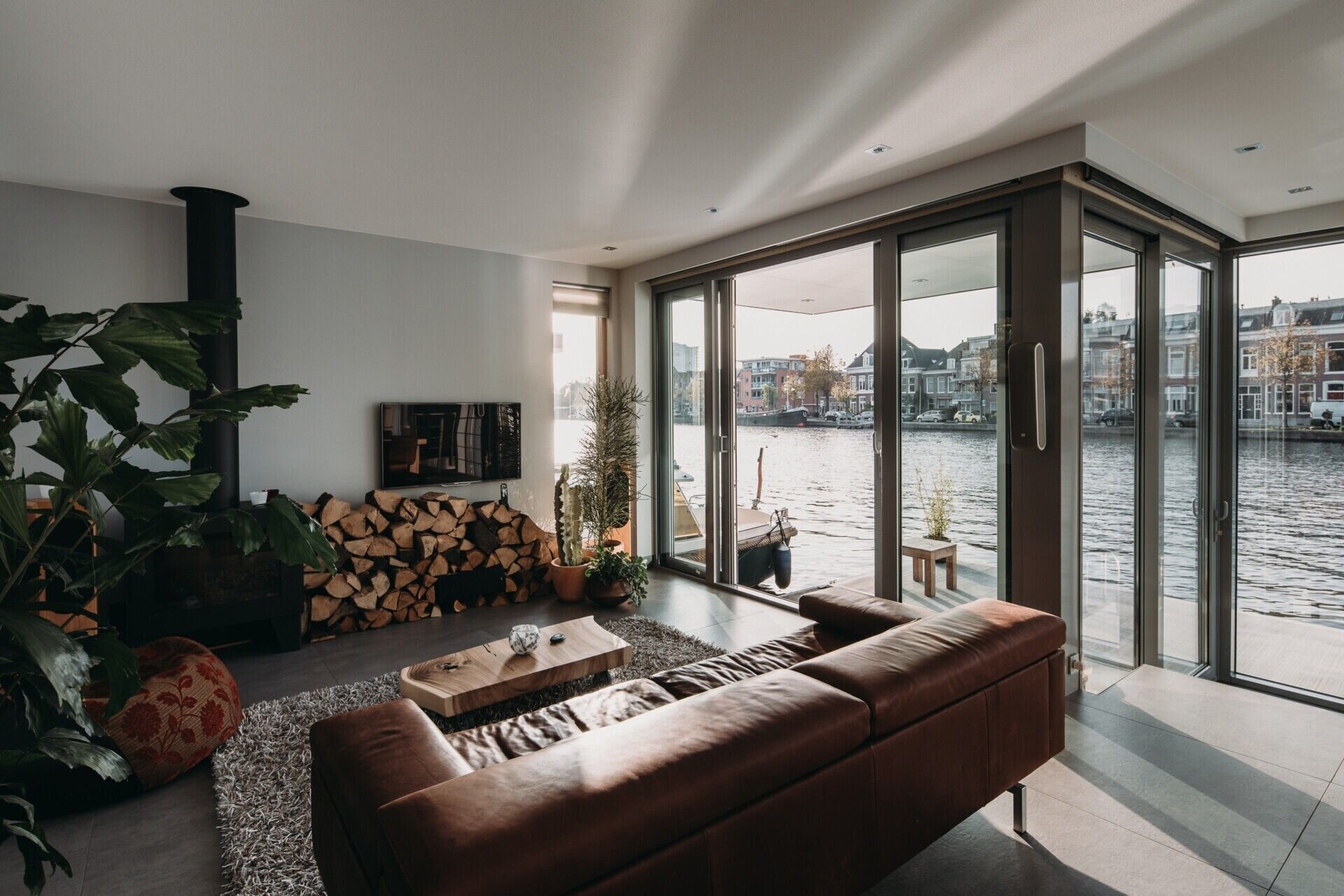 La acogedora sala de estar cuenta con una chimenea de leña y puertas correderas que conducen a una pequeña terraza junto al río.