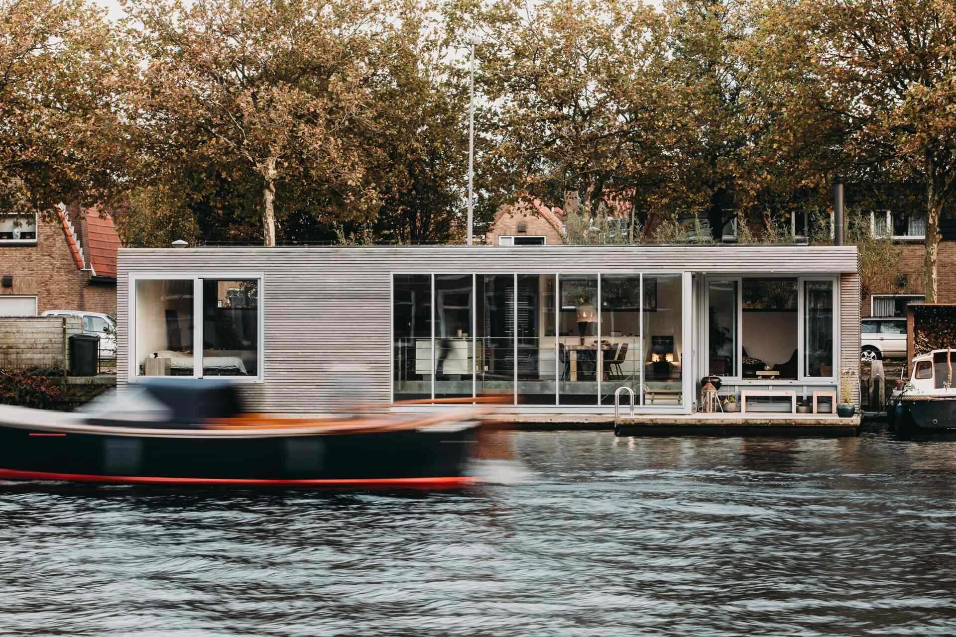 Una sorprendente villa flotante en Spaarne, con revestimientos de madera texturizada, finas molduras de aluminio y una brillante luz del suroeste dan forma al diseño.