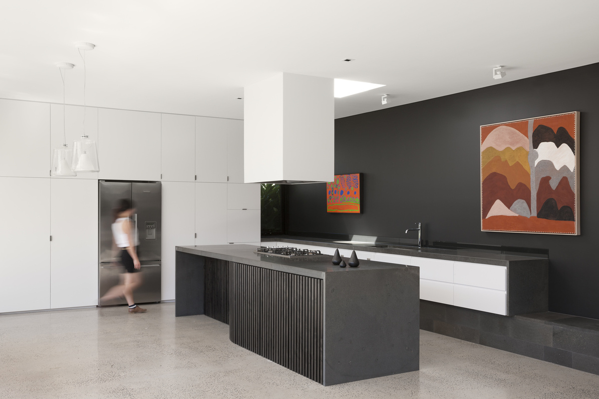 In this kitchen, a wall of white cabinets blends into the wall itself, surrounding the fridge and keeping the space uncluttered. The island adds more work space while keeping the layout open.