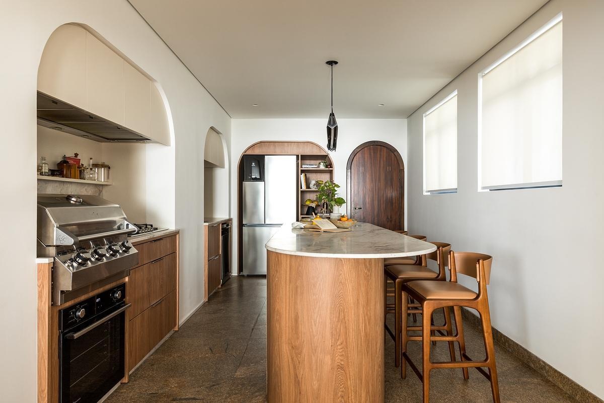 One of the homeowners’ biggest wishes was to make the kitchen the social heart of the apartment. Previously enclosed, it was opened to brighten circulation and connect it to daily life. A central island now anchors the space, paired with the Helga Bar Stool by Estudio Bola and the Wrap Lamp by Jader Almeida. Even appliances like the Char Broiler blend into the layout, keeping the look calm and unified.