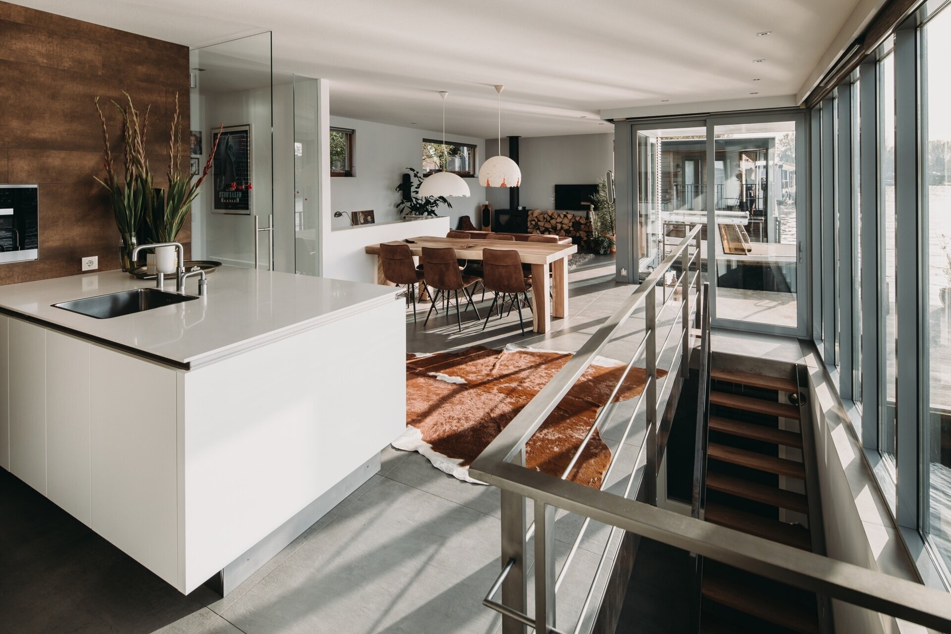 La cocina minimalista cuenta con gabinetes blancos y encimeras a juego, con vista directa al río y luz natural.