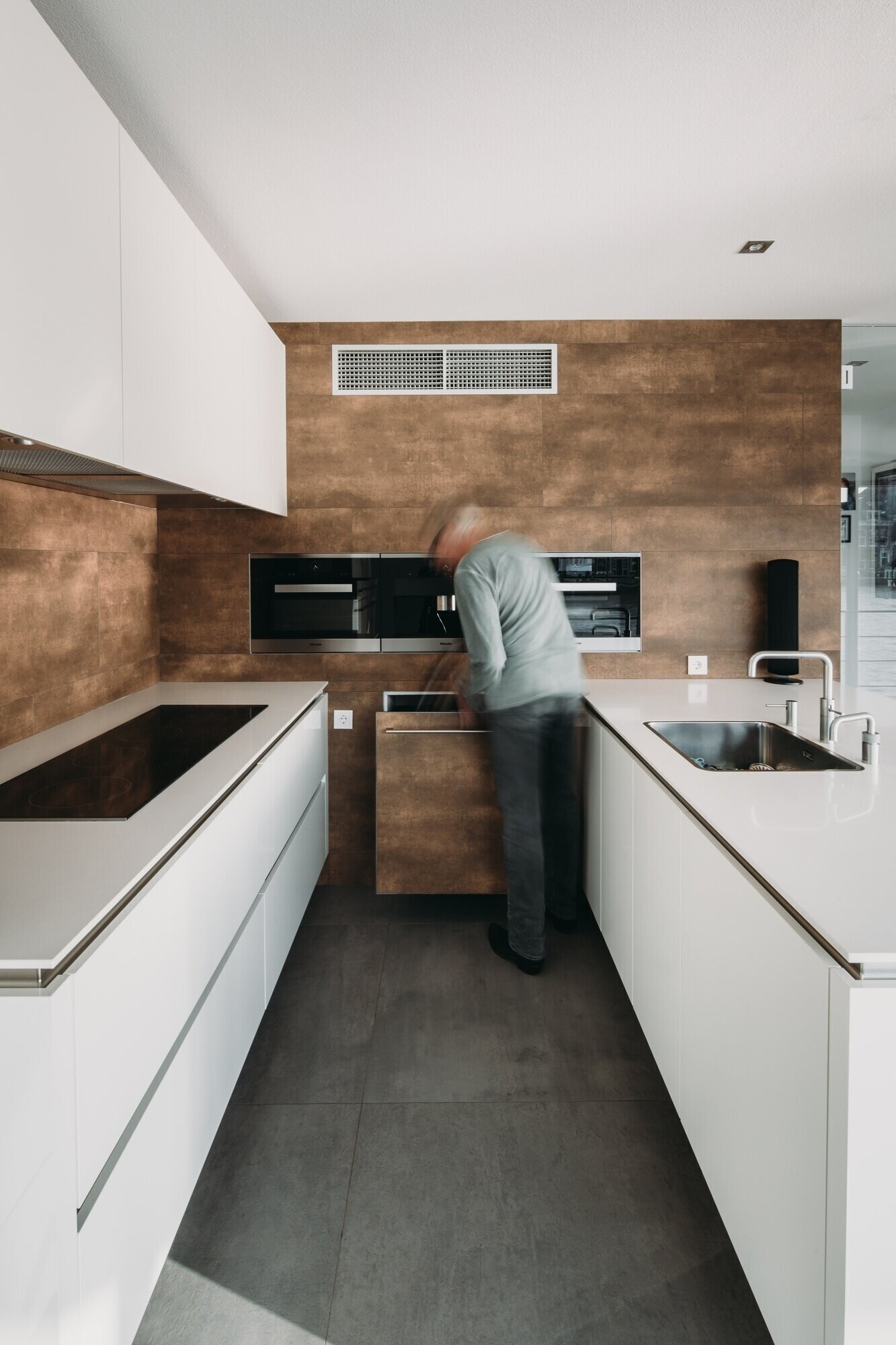 La cocina minimalista cuenta con gabinetes blancos y encimeras a juego, con vista directa al río y luz natural.