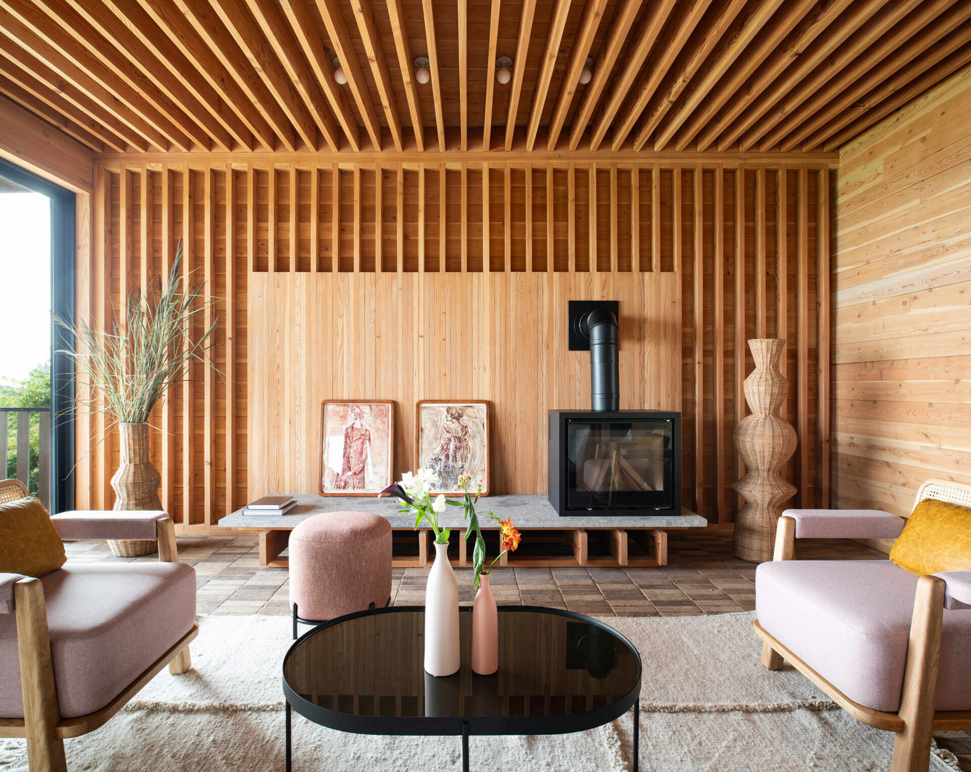 An honest, wood-framed living room where exposed beams, soft light, and a wood-burning stove define a space built for warmth and connection.