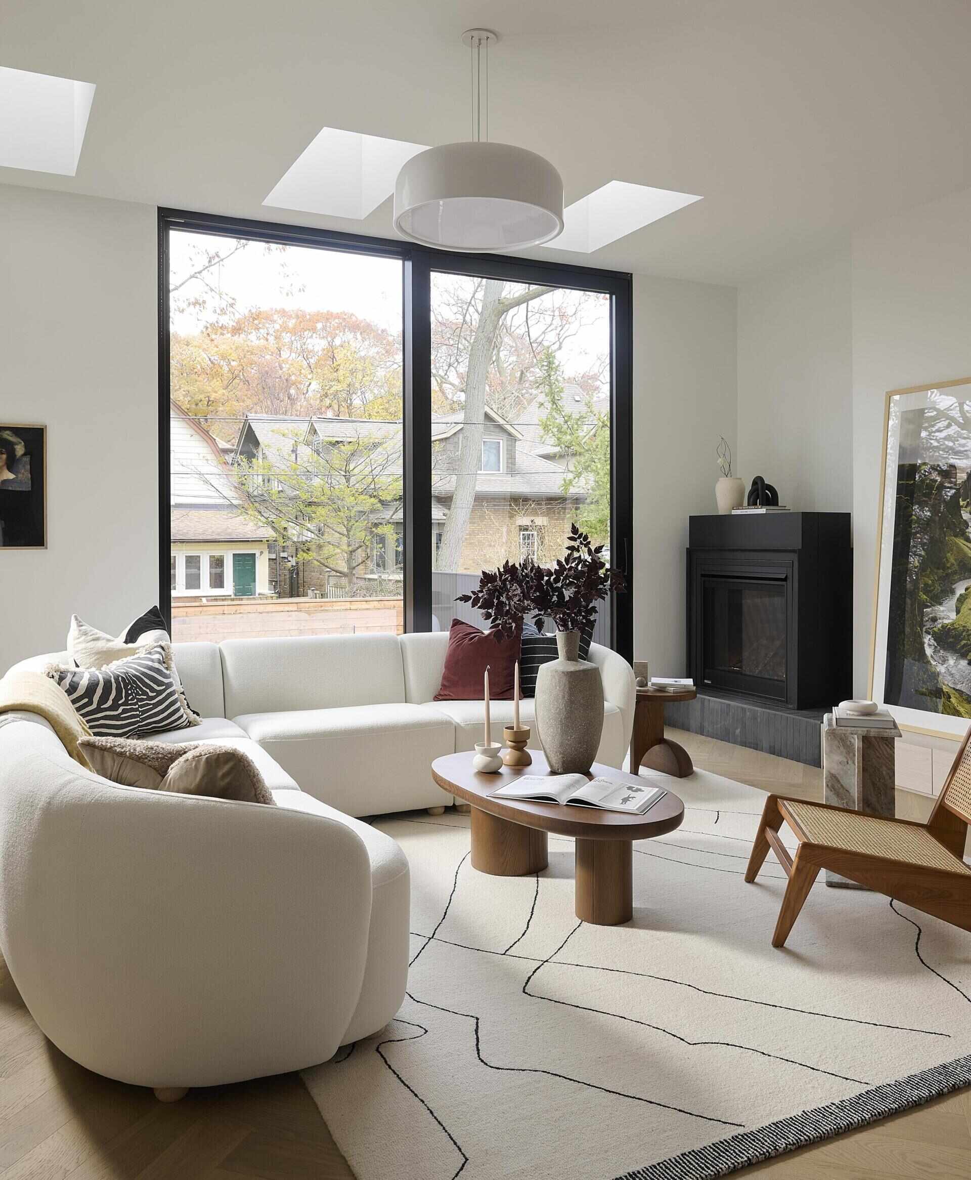At the back of the home, the living area opens fully to the outdoors through a sliding glass door. Three skylights soften the room with overhead light. A freestanding black fireplace sits on a black brick and white oak hearth.