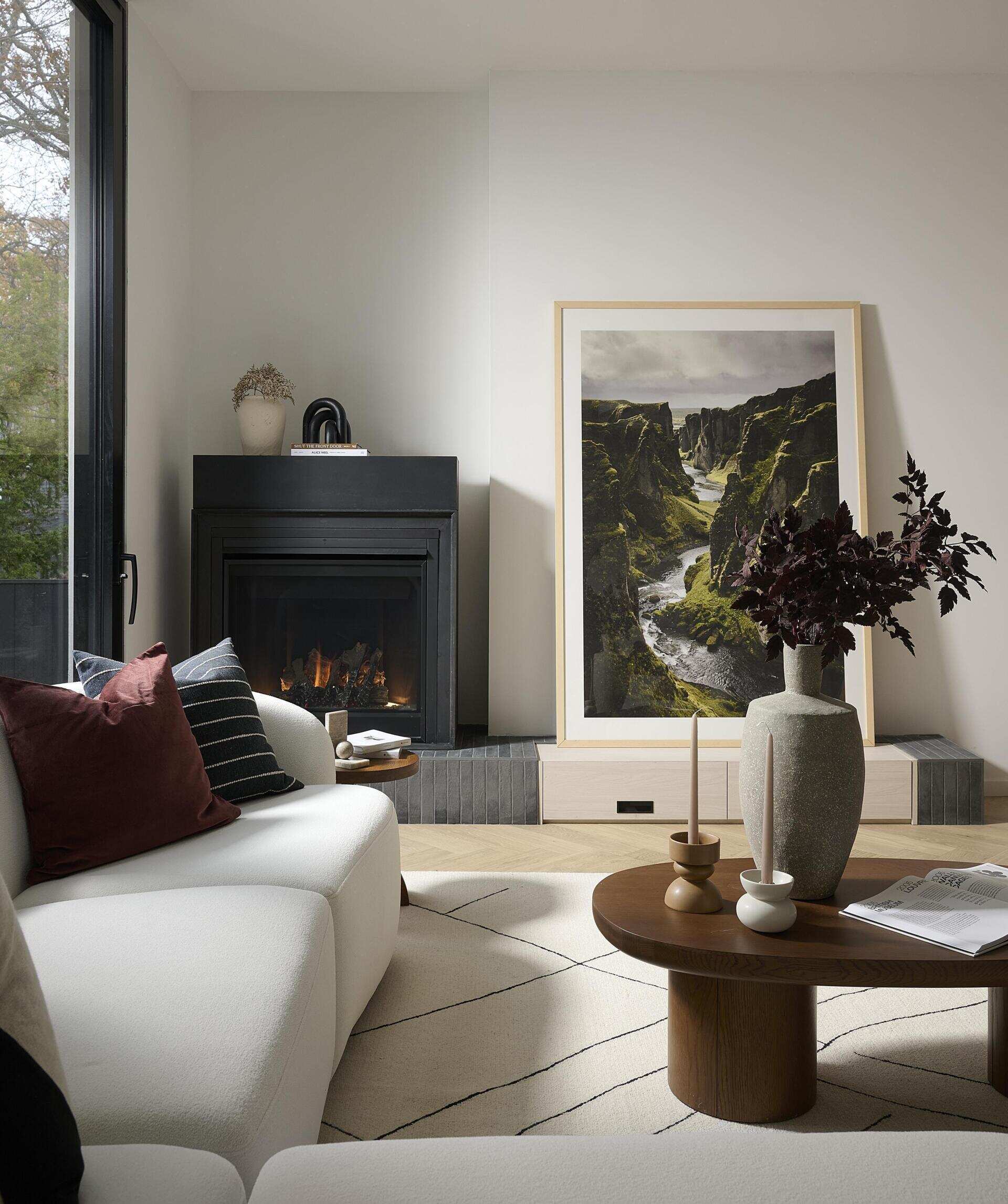 At the back of the home, the living area opens fully to the outdoors through a sliding glass door. Three skylights soften the room with overhead light. A freestanding black fireplace sits on a black brick and white oak hearth.